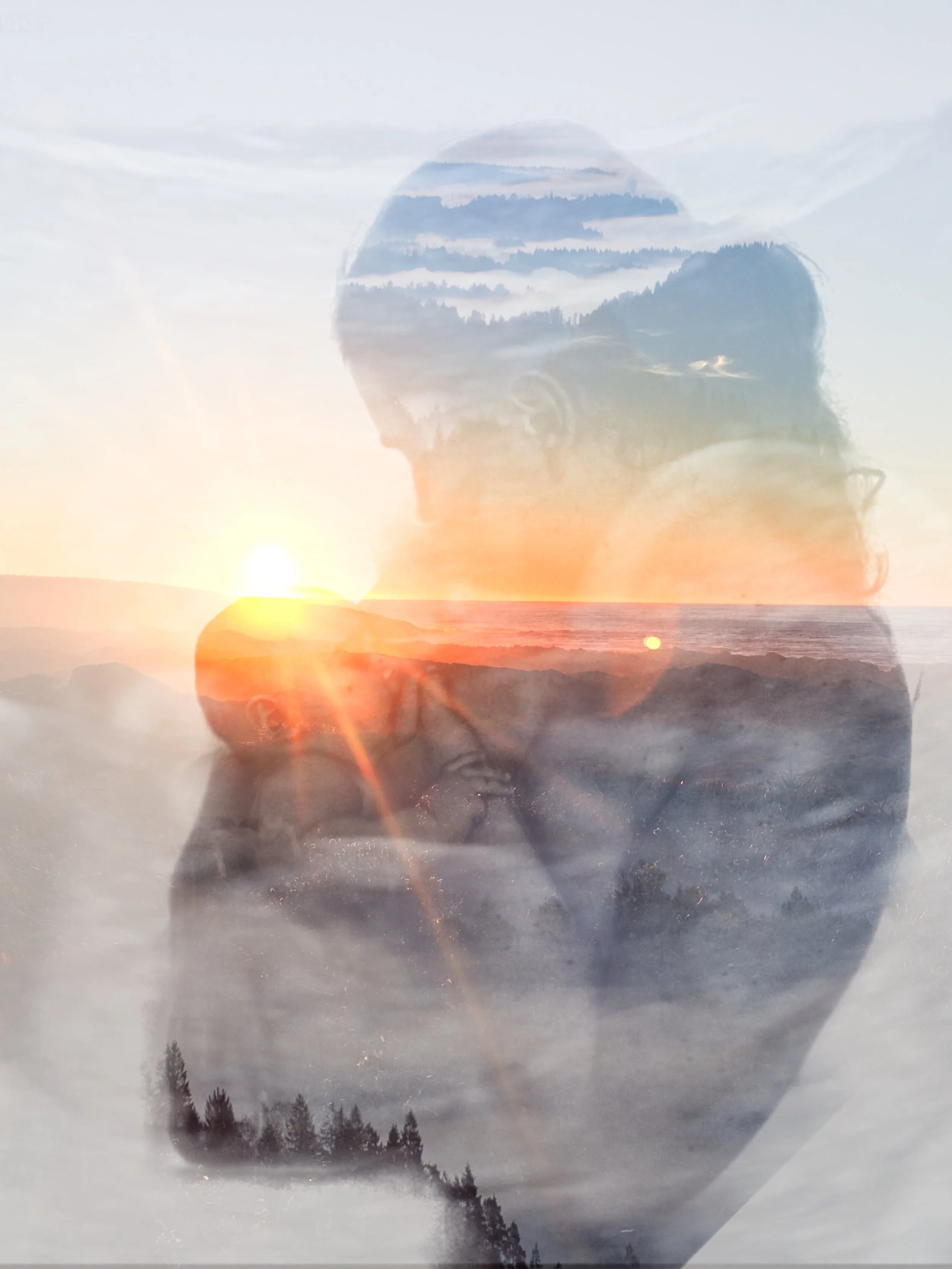 A double exposure image of a woman with a mountain landscape and ocean scene superimposed on her profile during sunset.