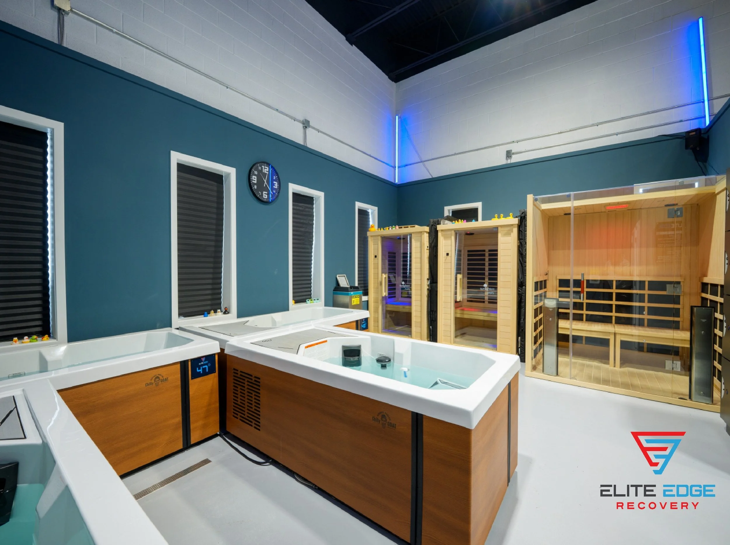 a room that is filled with different recovery modalities like, ice baths, cold plunges, hot tubs. and infrared saunas. the room is blue in color with blue lights making for a relaxing and calming environment near Paoli, PA.