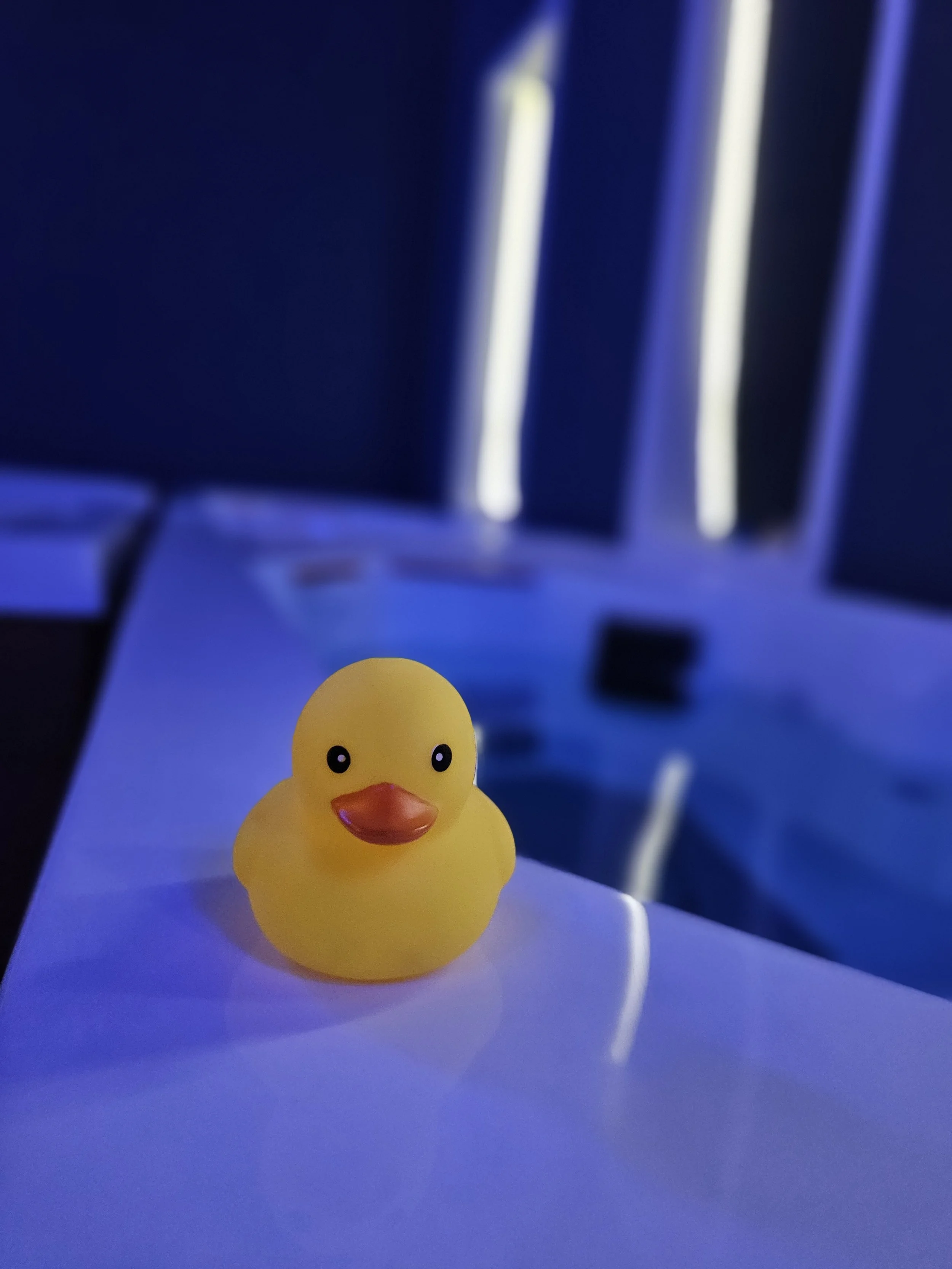Yellow rubber duck on an Ice bath with a blurred dark background and vertical light streaks.