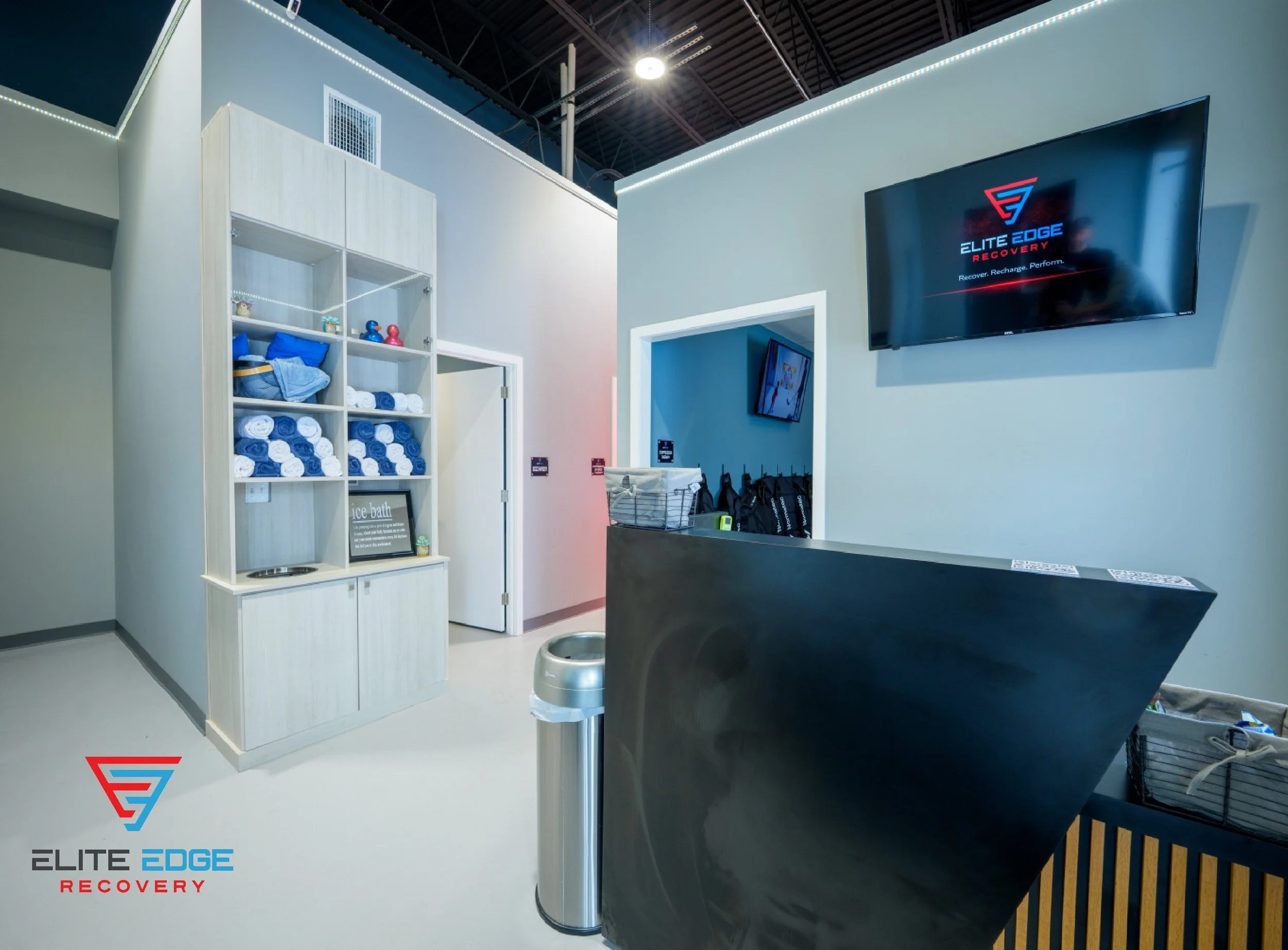 A photo of the front lobby to Elite Edge Recovery featuring a black desk, a tv, and a shelf that has towels on it. Located near Frazer, PA.