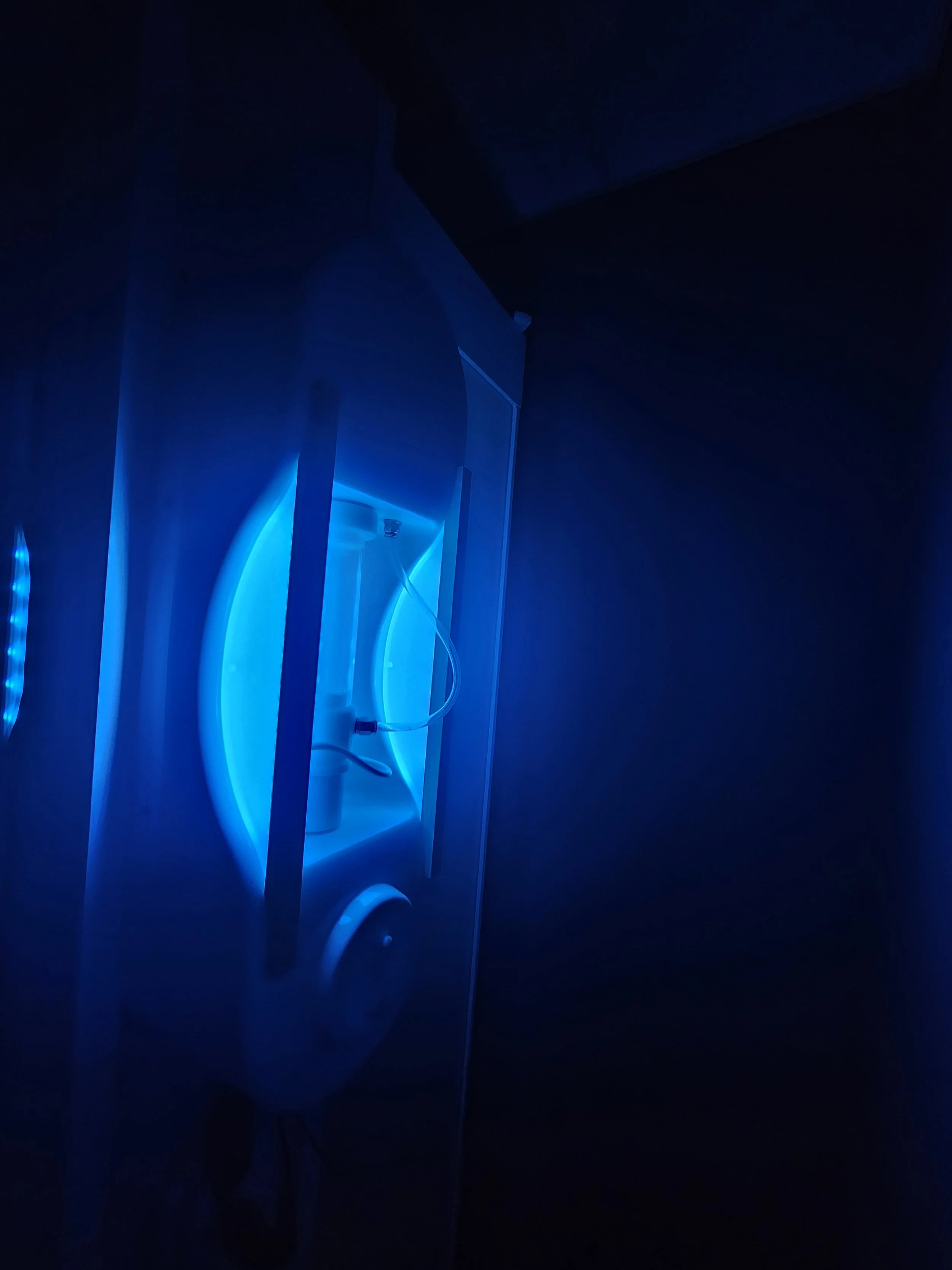 A blue-lit tanning bed in a dark room.
