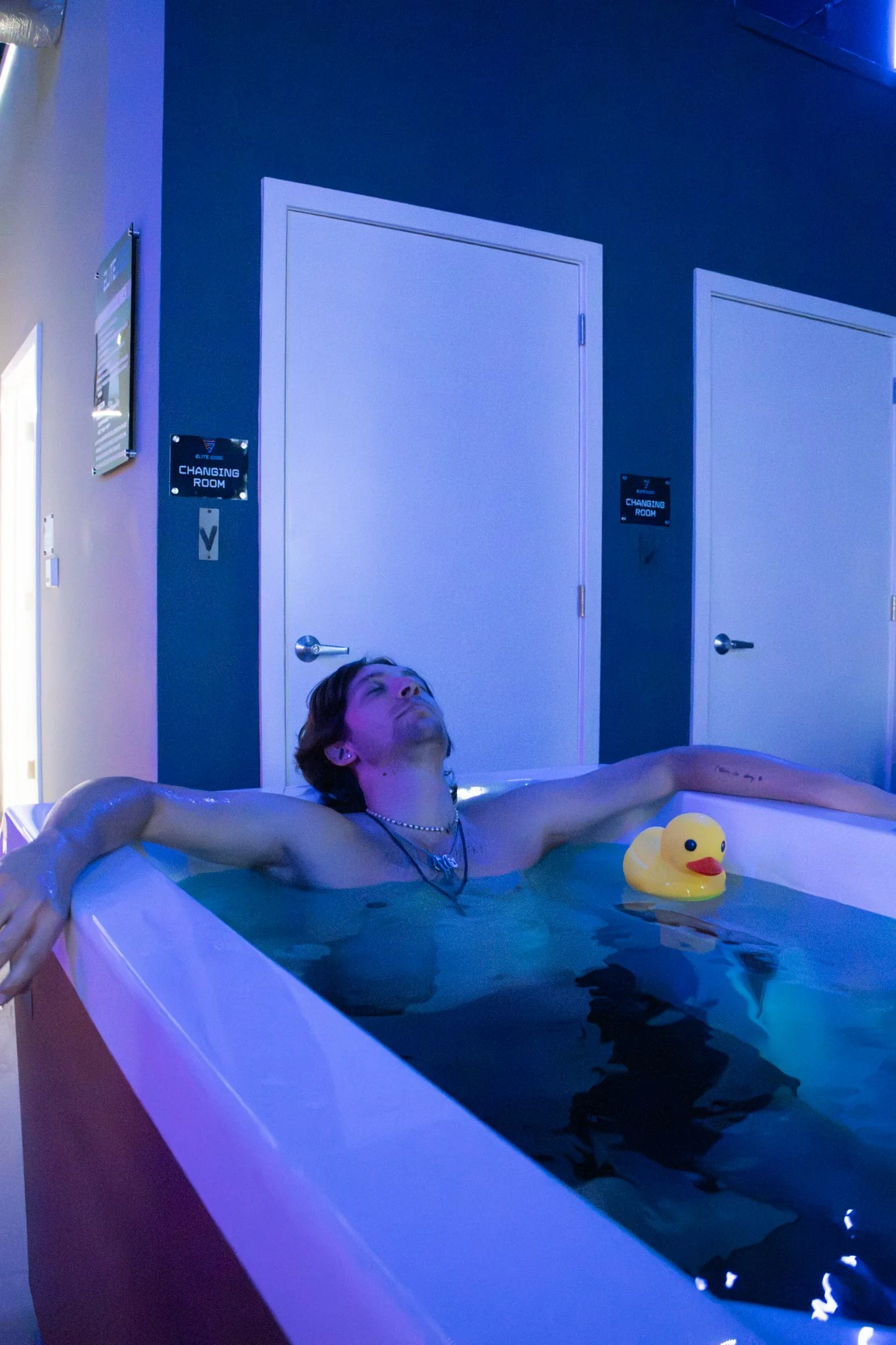 A man leaning back in a hot tub in a room with blue lights. He also has a rubber duct in the hot tub with him Located near Chester Springs, PA.