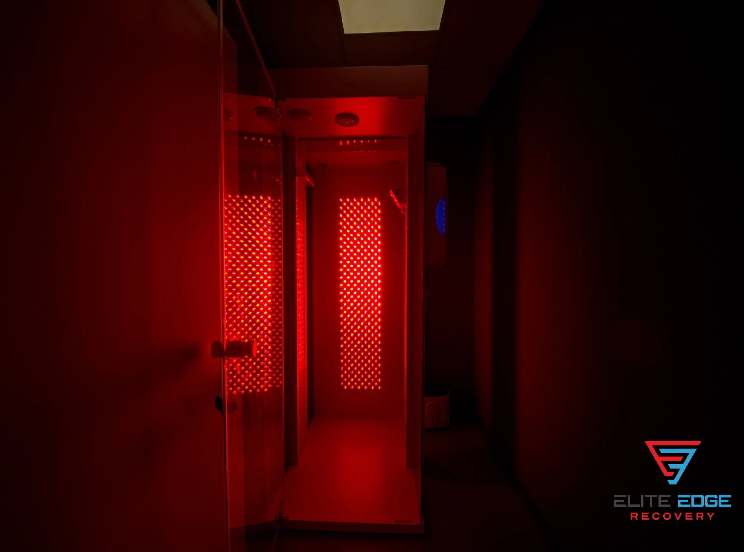 A dark room with red LED lights and reflection in mirrored walls. Text in the lower right corner reads 'elite edge recovery'. The therapy room is a Red Light Therapy and Halo therapy room located near Exton, PA.