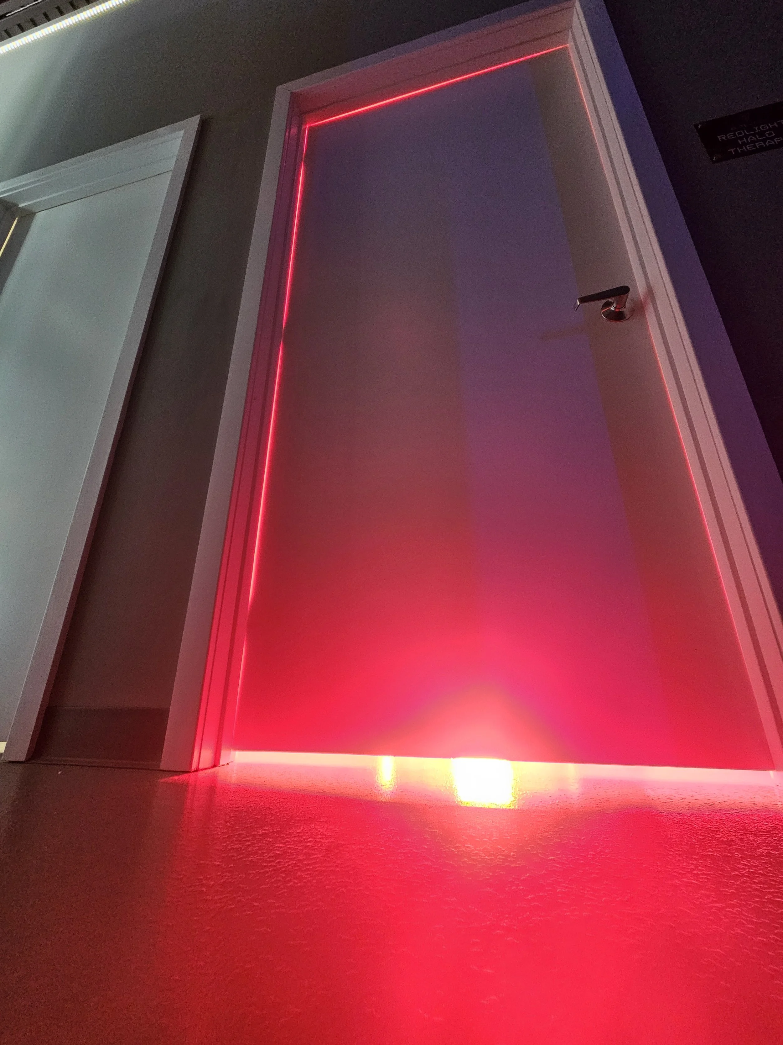 A door with red LED lighting along the edges, partly open, revealing a dimly lit interior.