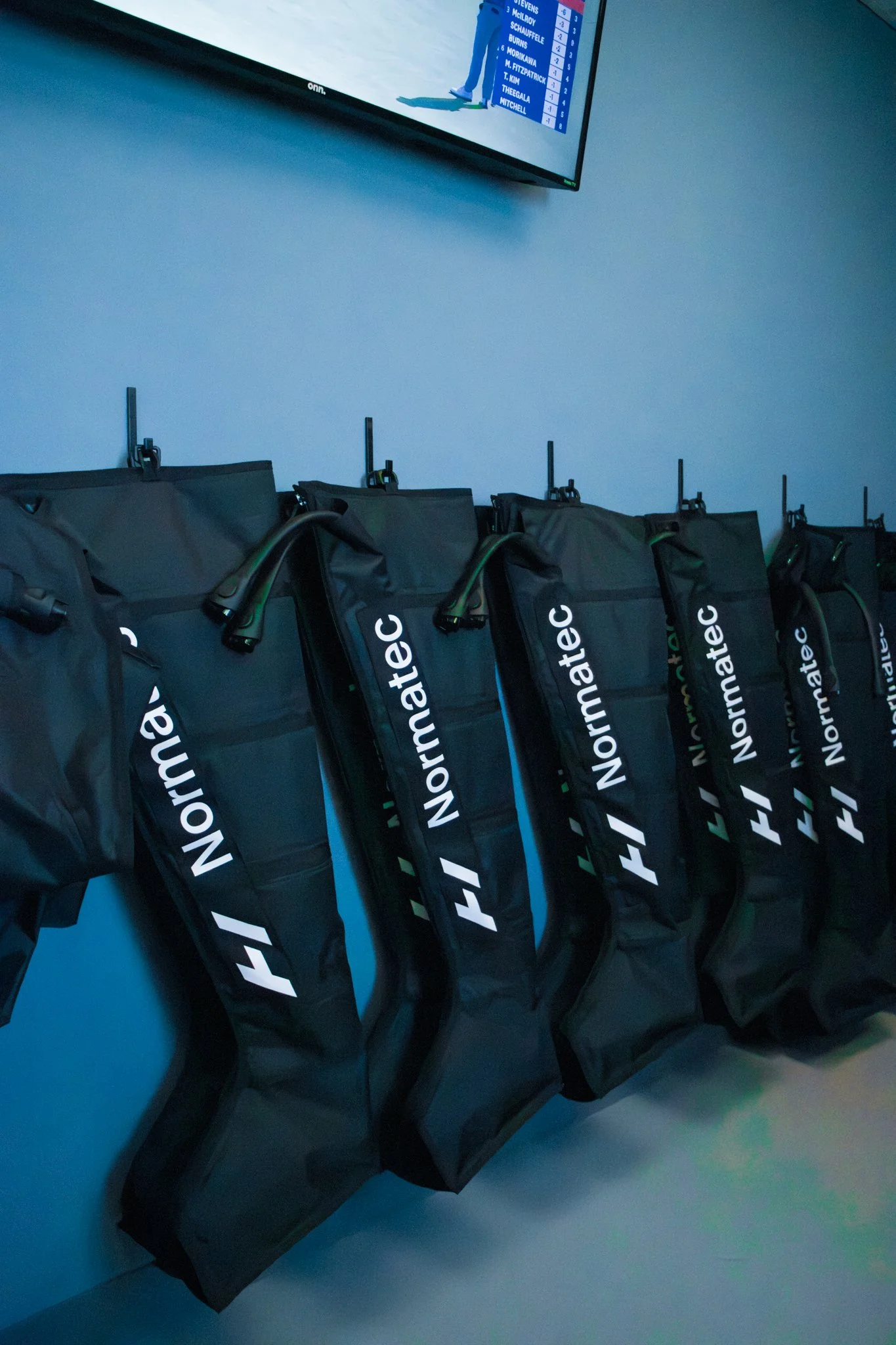 an image of Normatec compression boots hanging on a blue wall in a recovery room located near Frazer, PA.