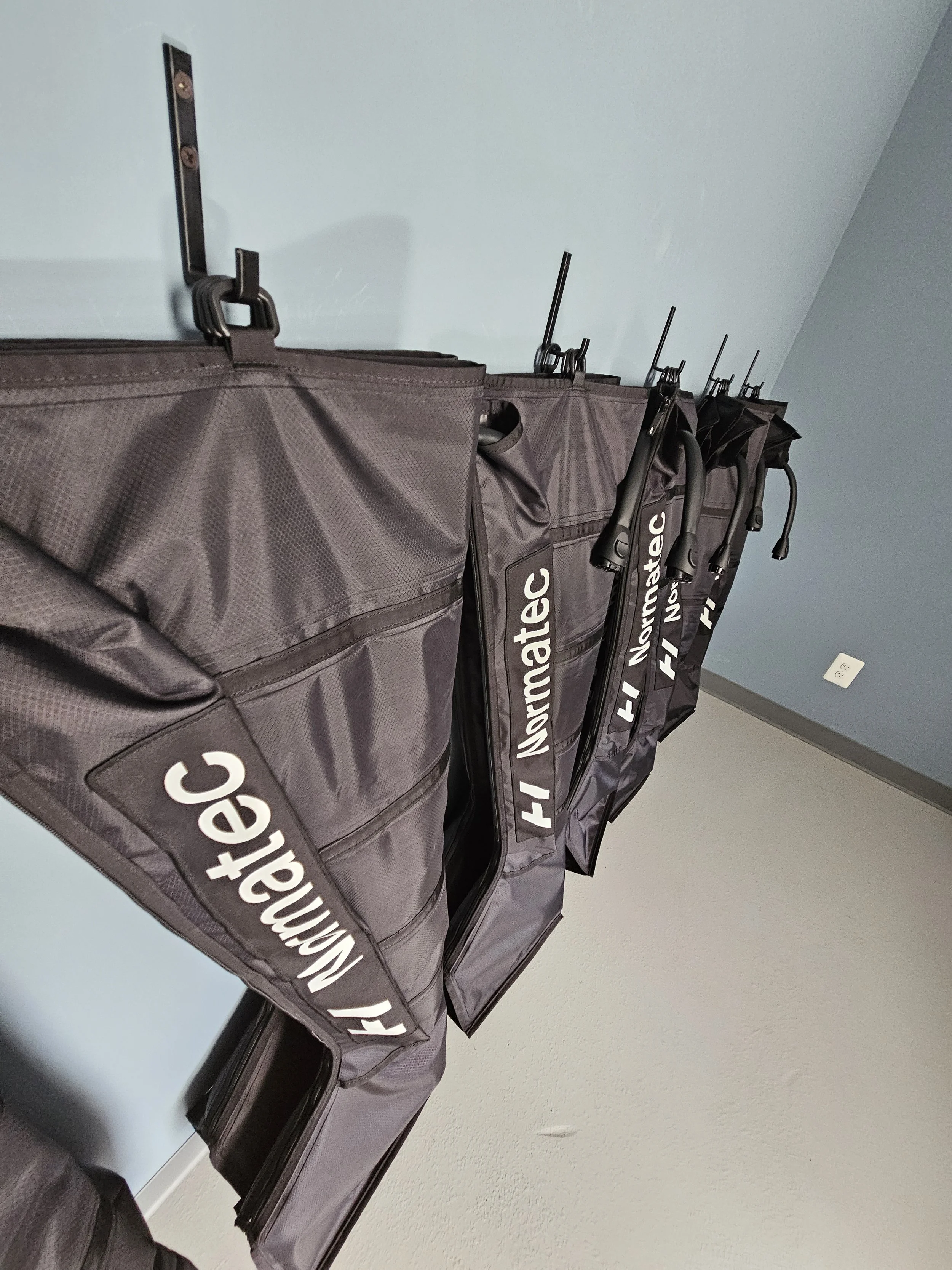 Multiple Aeromate bags hanging on hooks on a light blue wall.