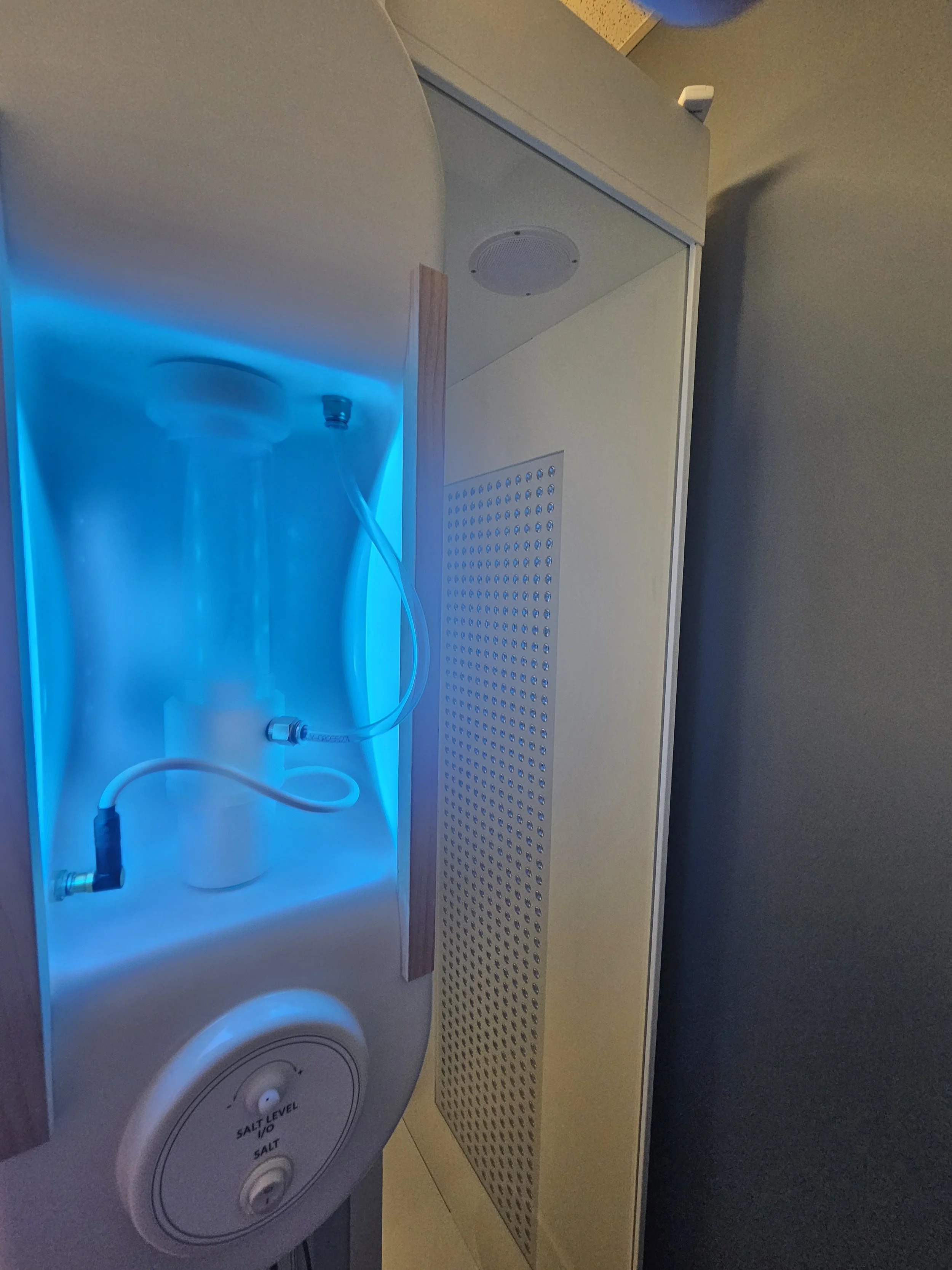 A medical or laboratory device with a glowing blue light, a transparent tube, and a control knob labeled 'Salt Level'. that is used to release halo therapy into a booth located in Malvern, PA.