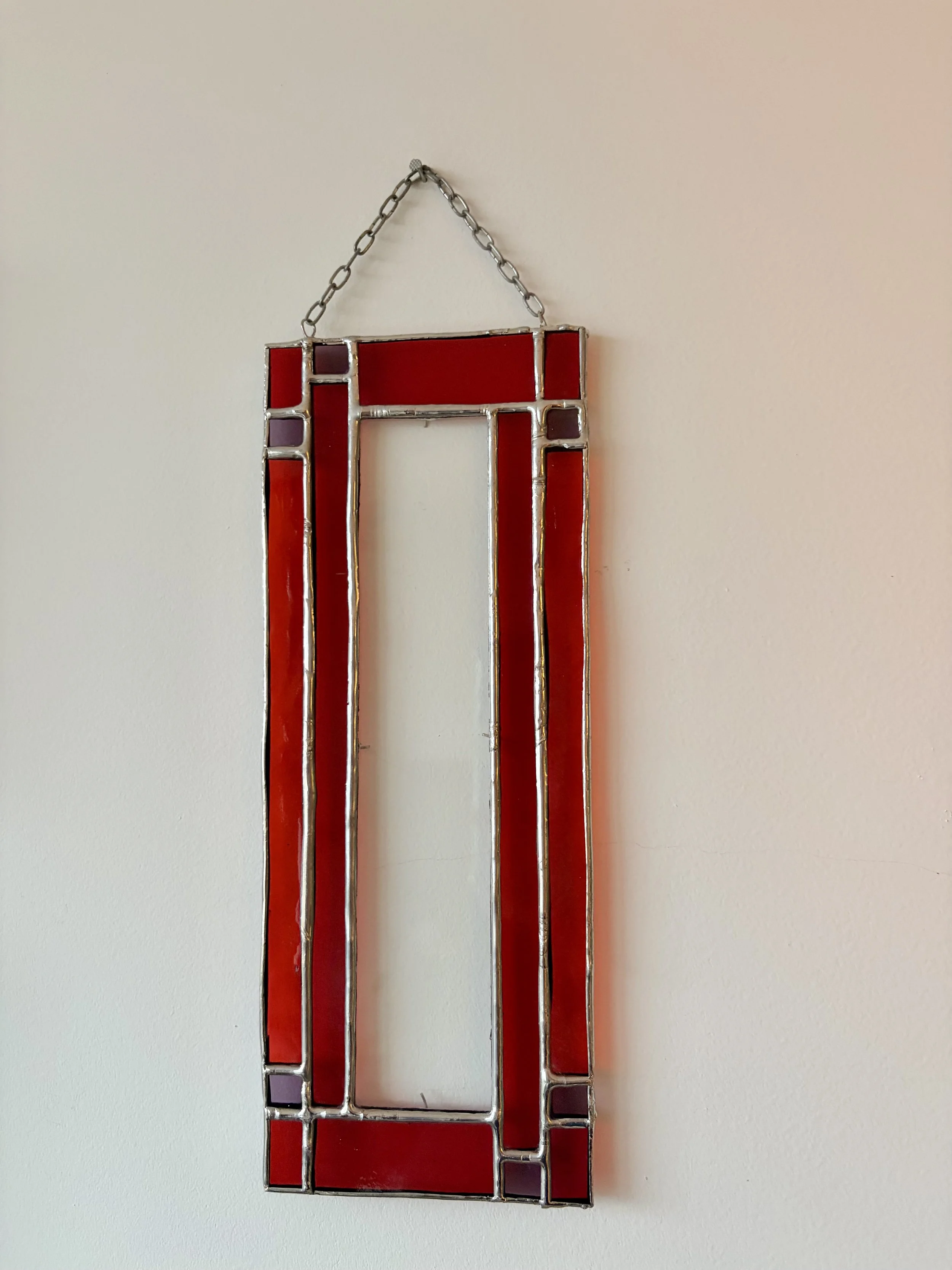 Een fotolijstje van glas in lood, met de kleuren rood en paars, wordt omhoog gehouden.