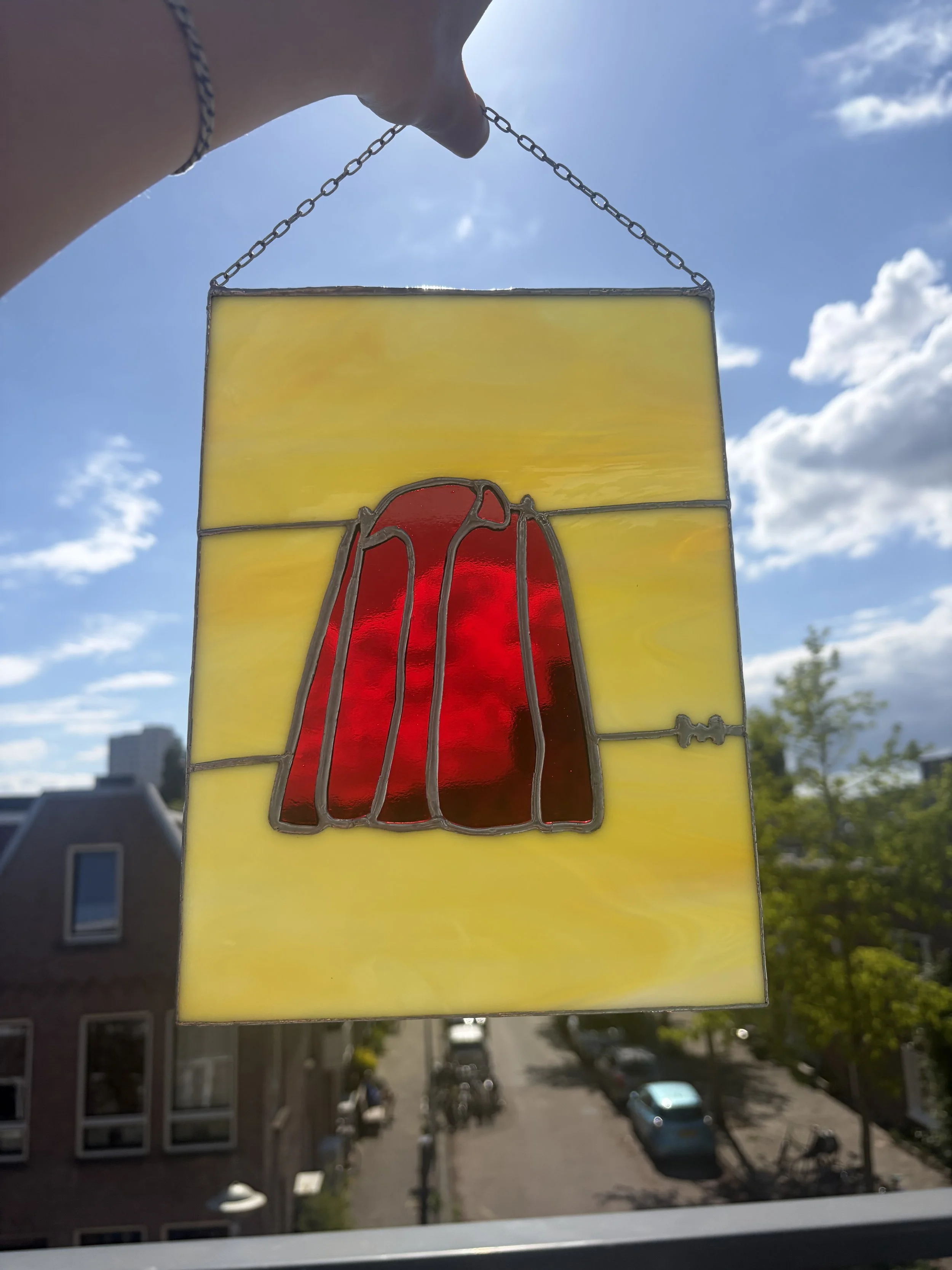 Glas in lood kunst van een rood jasje met een gele achtergrond.