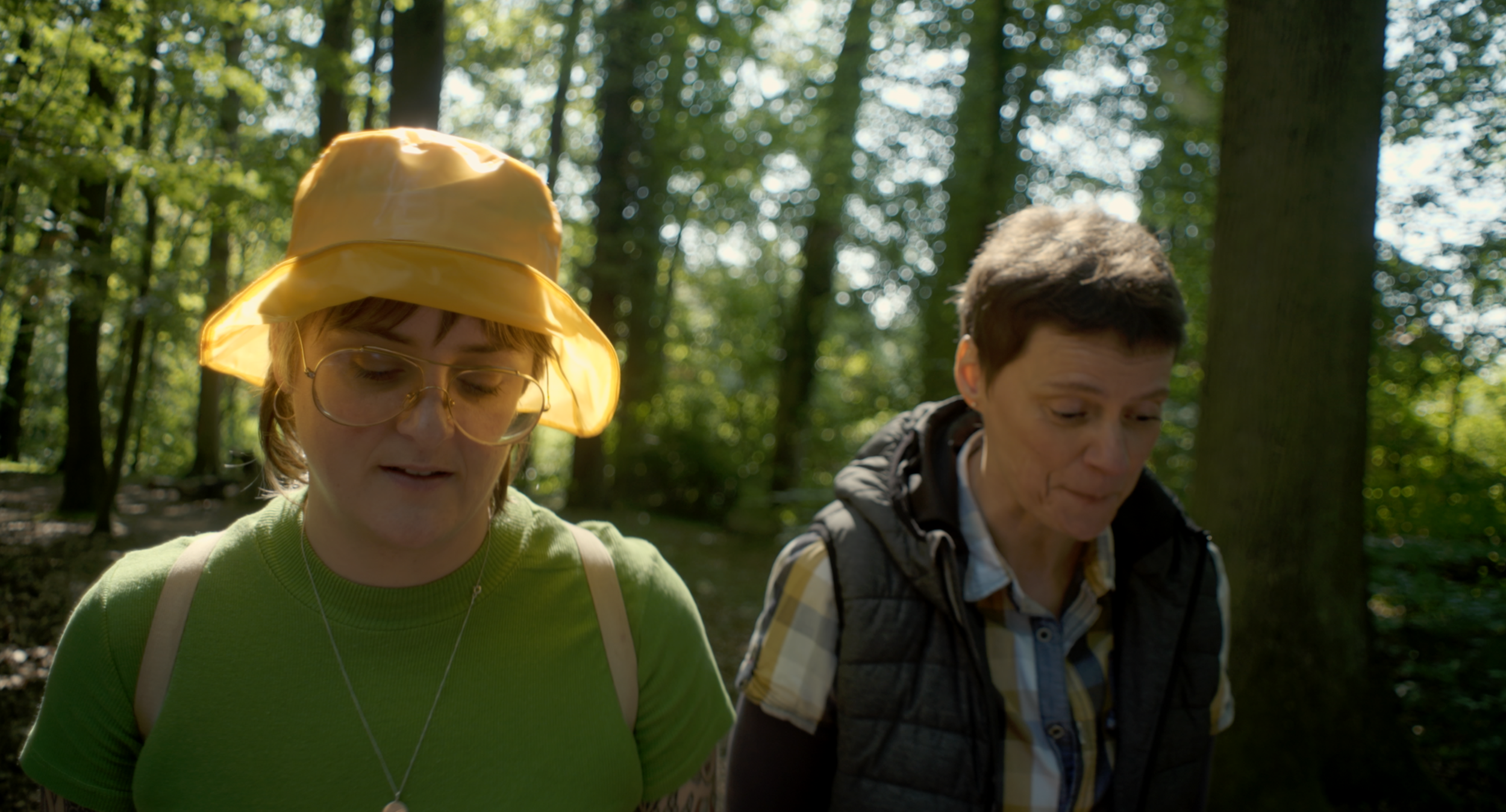 Zwei Frauen wandern im Wald an einem sonnigen Tag.