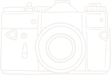 A white line drawing of a vintage camera with a large lens in the center and various control buttons.