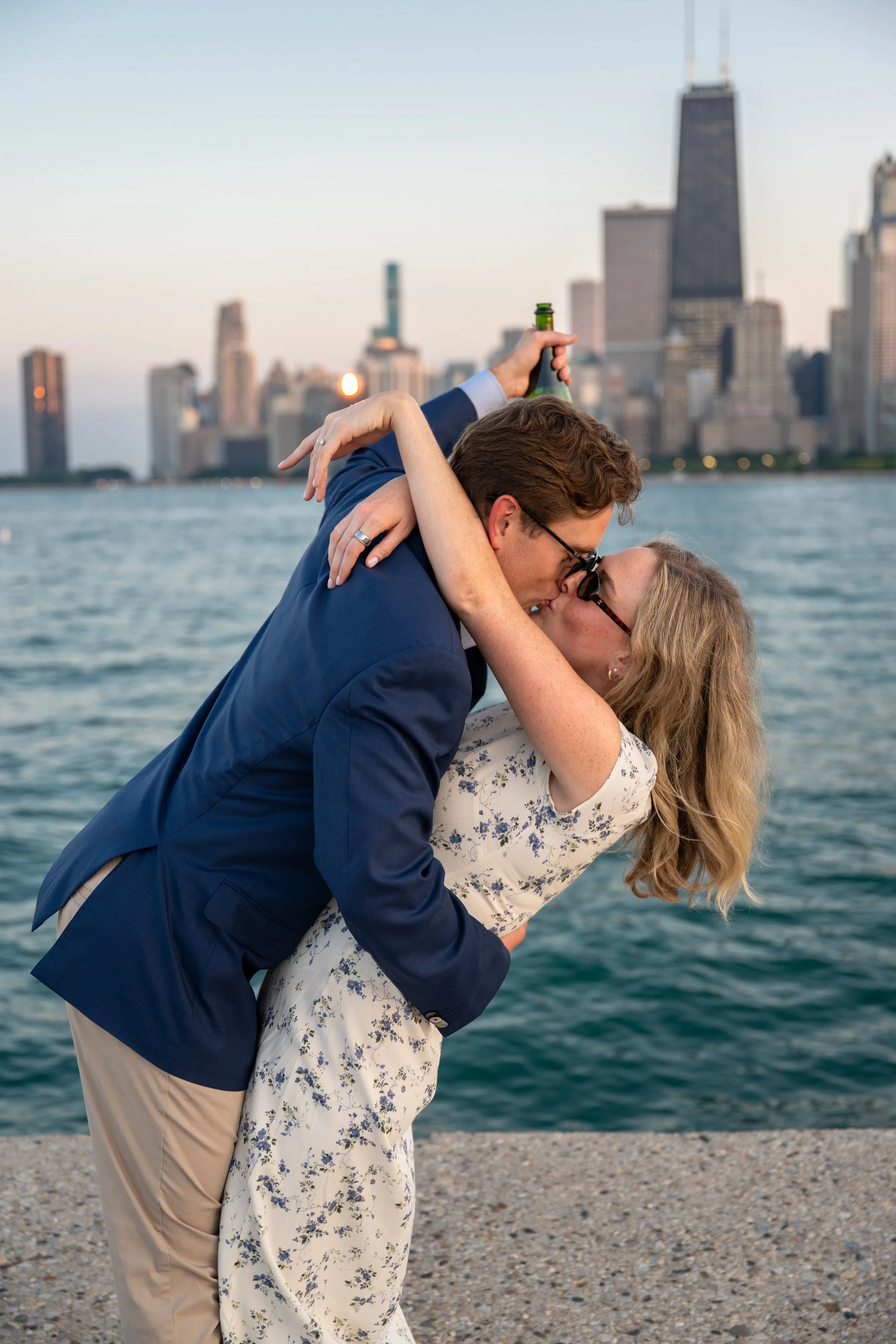 A couple sharing a kiss near Lake Michigan with the Chicago skyline in the background.