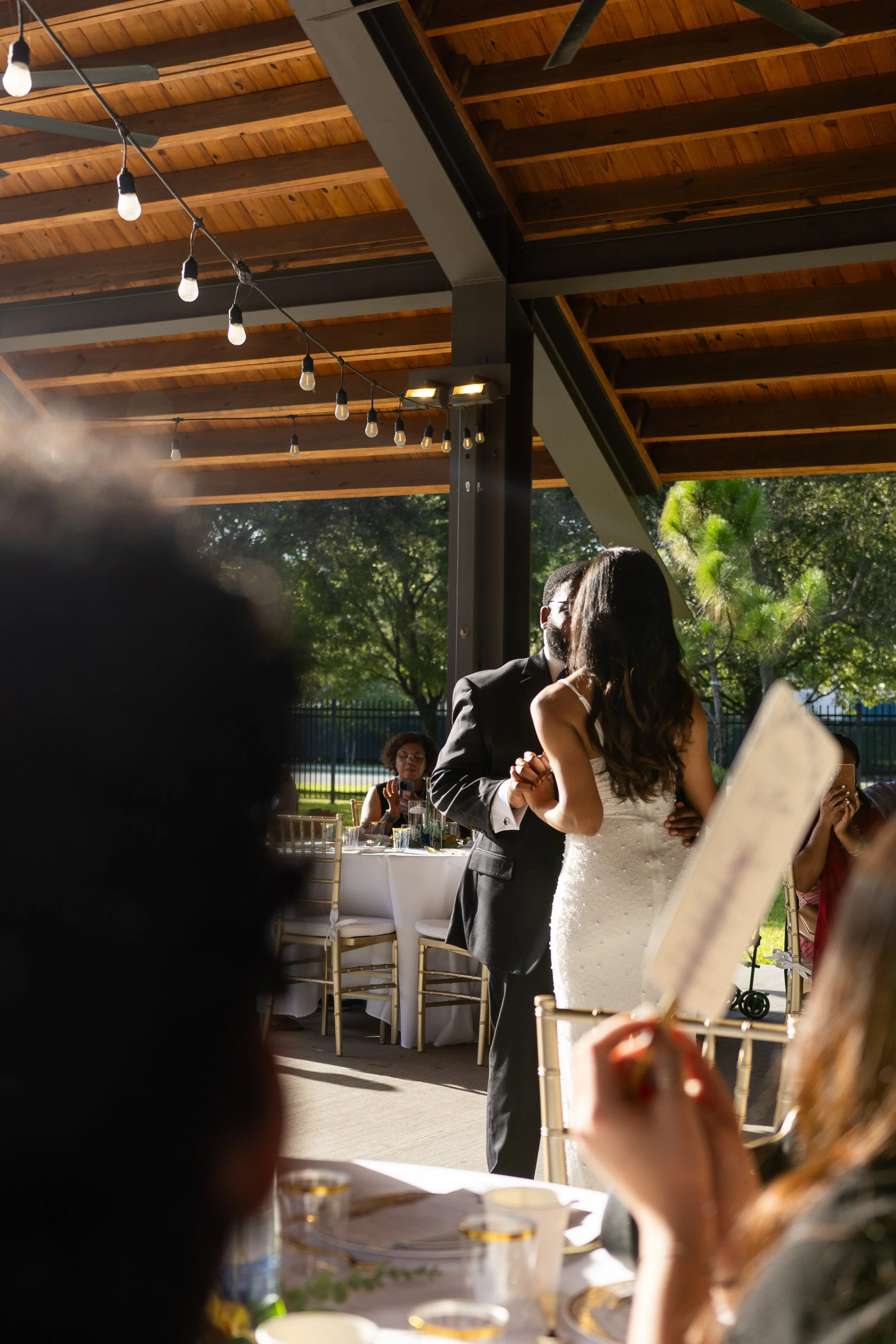 A couple's first dance beneath an outdoor gazebo at sunset.