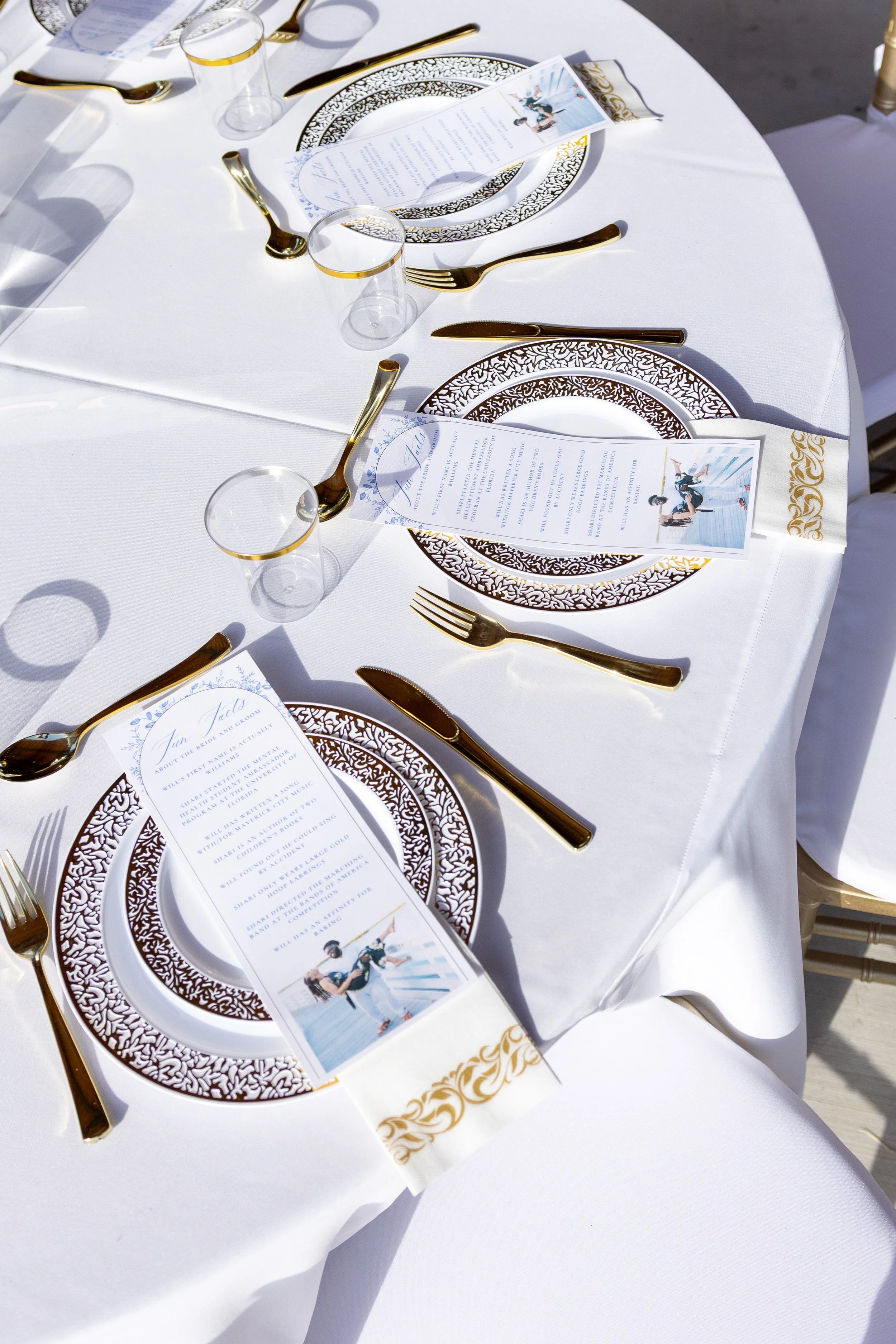 Aerial shot of a reception table with plates, menu cards, cups, and utensils.