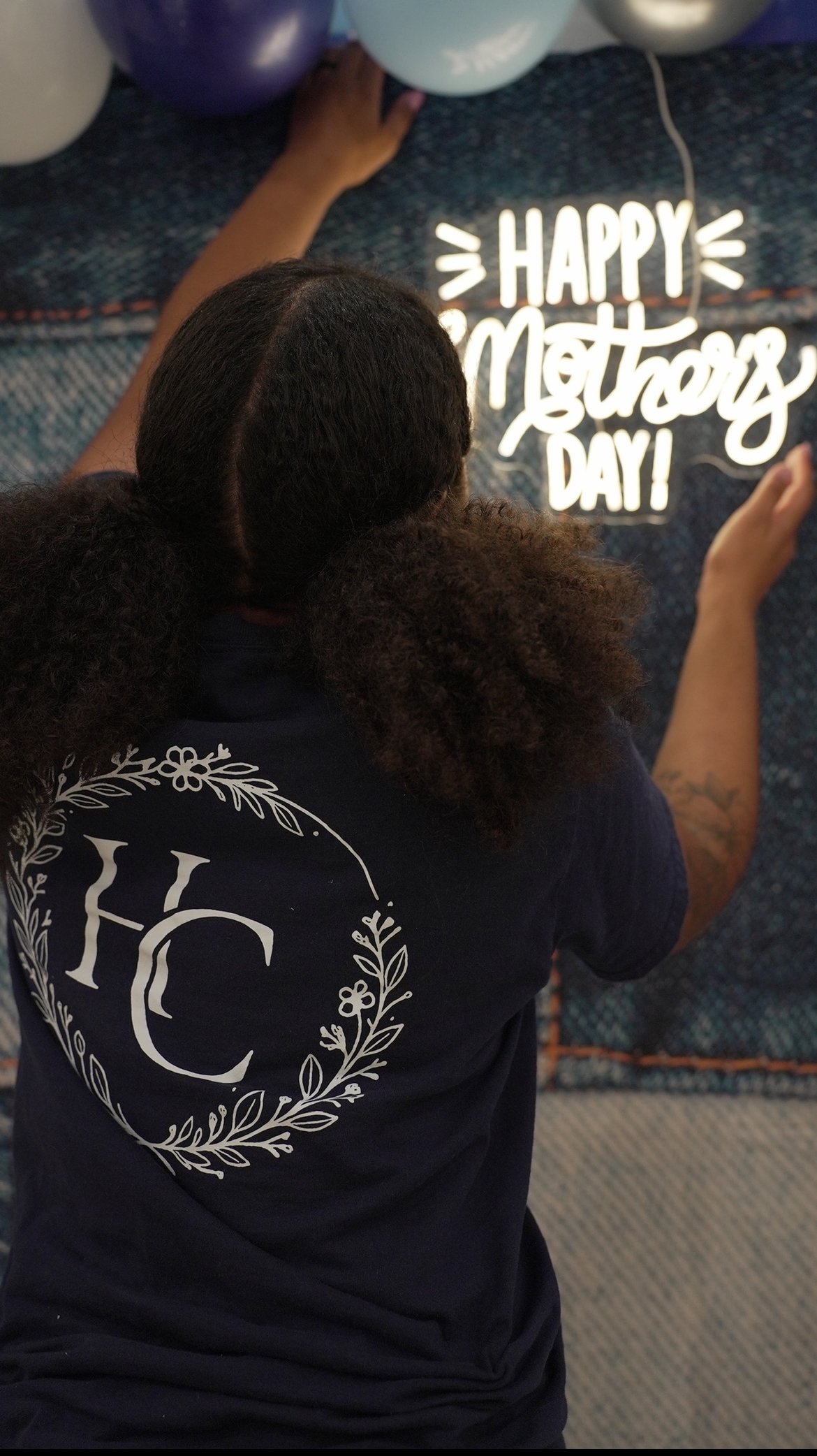 Helen Charlton preparing a neon sign display for a Mother's Day celebration.