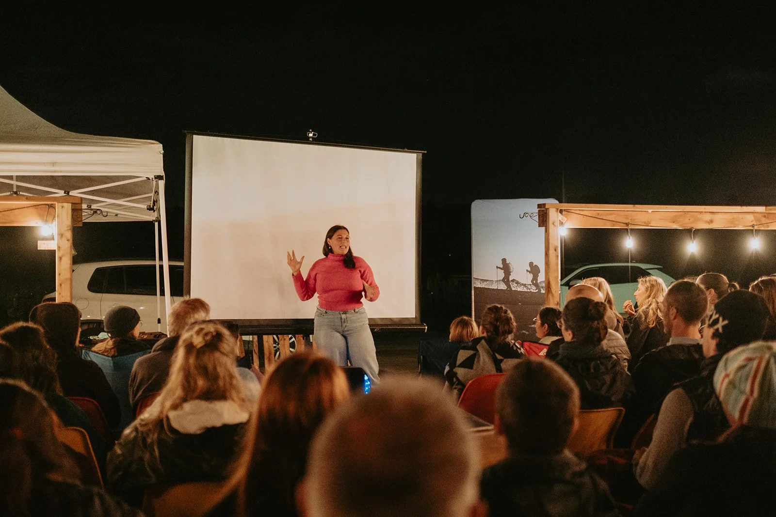 Anabelle Guay parle devant un groupe de personnes assises en extérieur, lors d'une soirée avec éclairage chaleureux