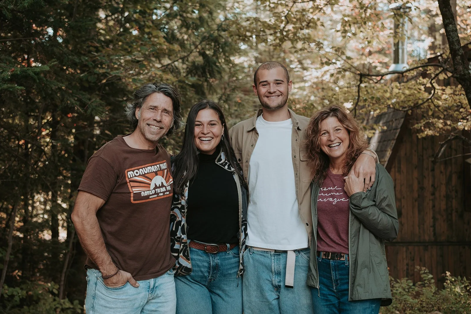Groupe de cinq personnes souriantes posant ensemble dans un jardin avec des arbres aux feuilles d'automne.