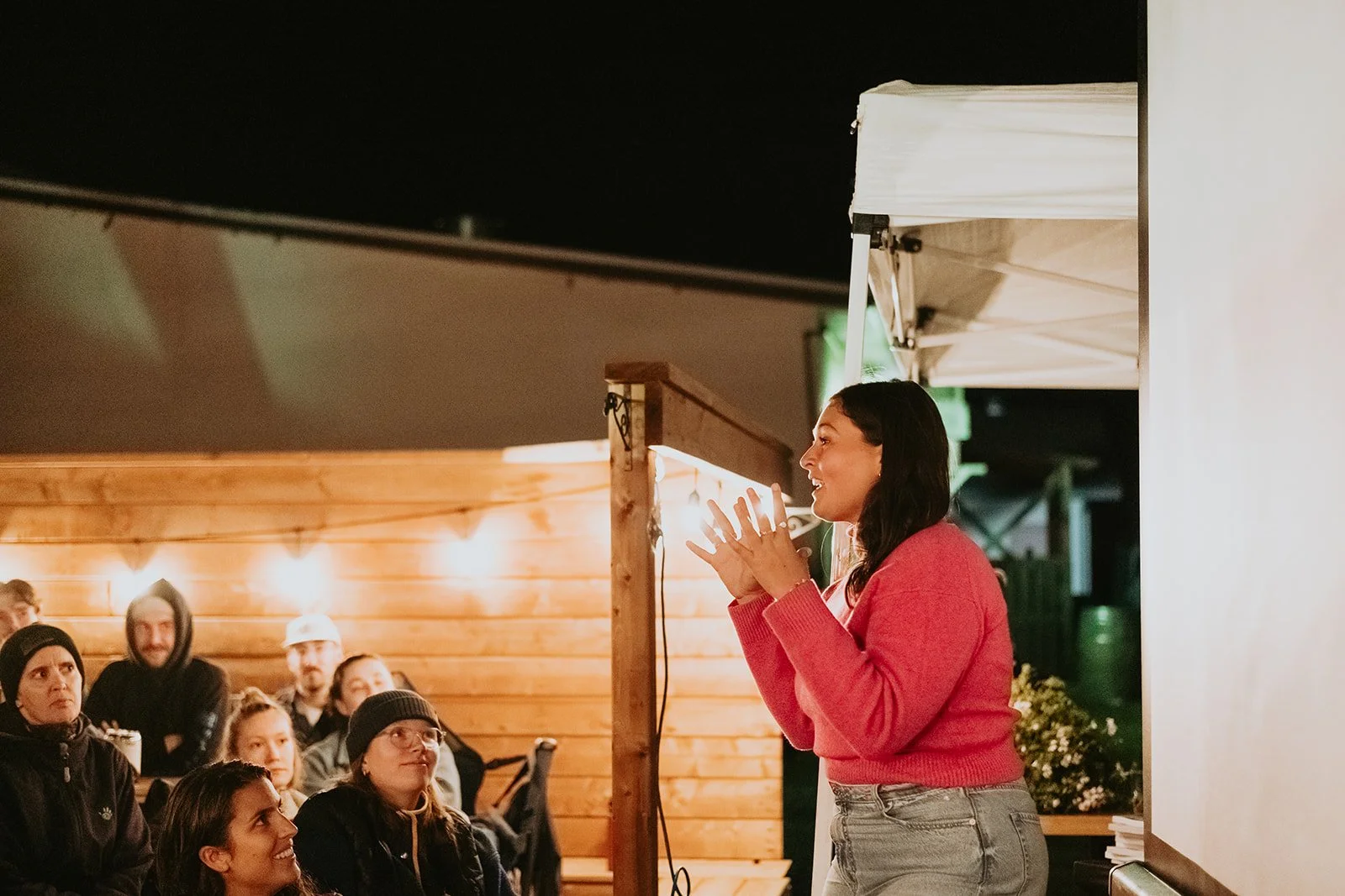 Vue de la côte avec des falaises couvertes d'arbres et l'océan au loin, en partie obscurcie par des fleurs et des feuilles au premier plan.
