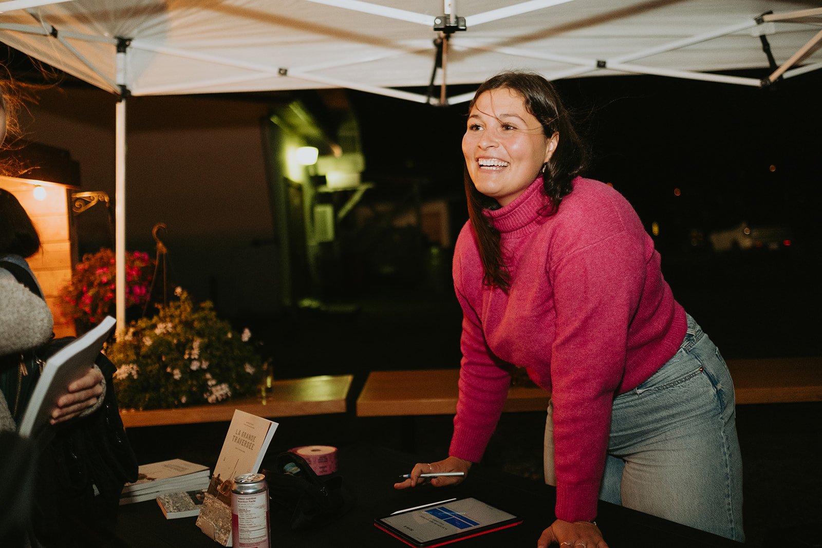 Côte rocheuse avec des arbres verts, fleurs blanches au premier plan, mer grise et ciel nuageux, un oiseau en vol.
