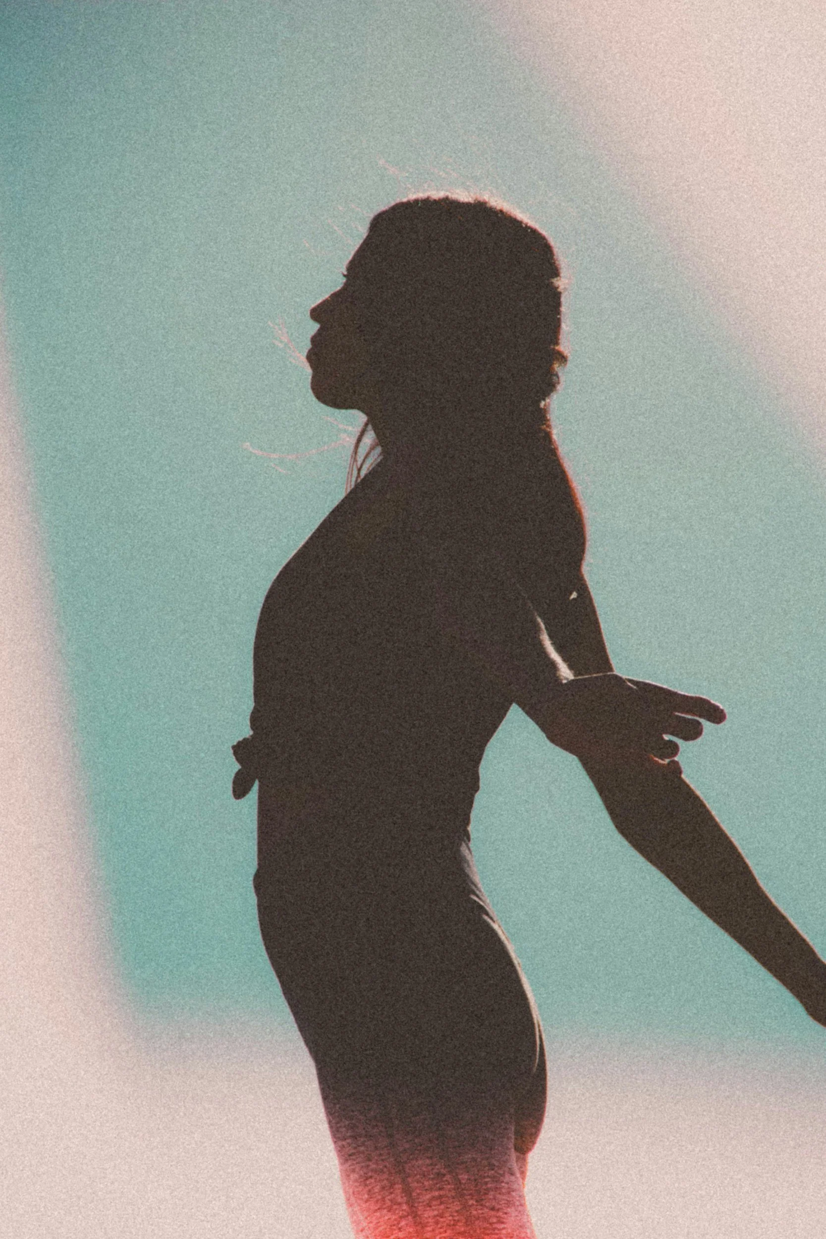 A silhouette of a person in a stretching or dancing pose against a gradient background of blue, pink, and purple hues.