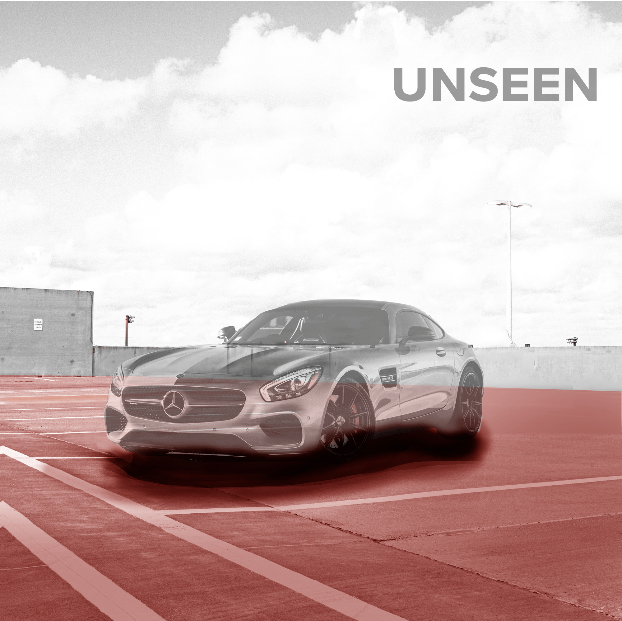 A sleek silver Mercedes-Benz sports car parked in an empty rooftop parking lot under a cloudy sky, with the word 'UNSEEN' in the top right corner.
