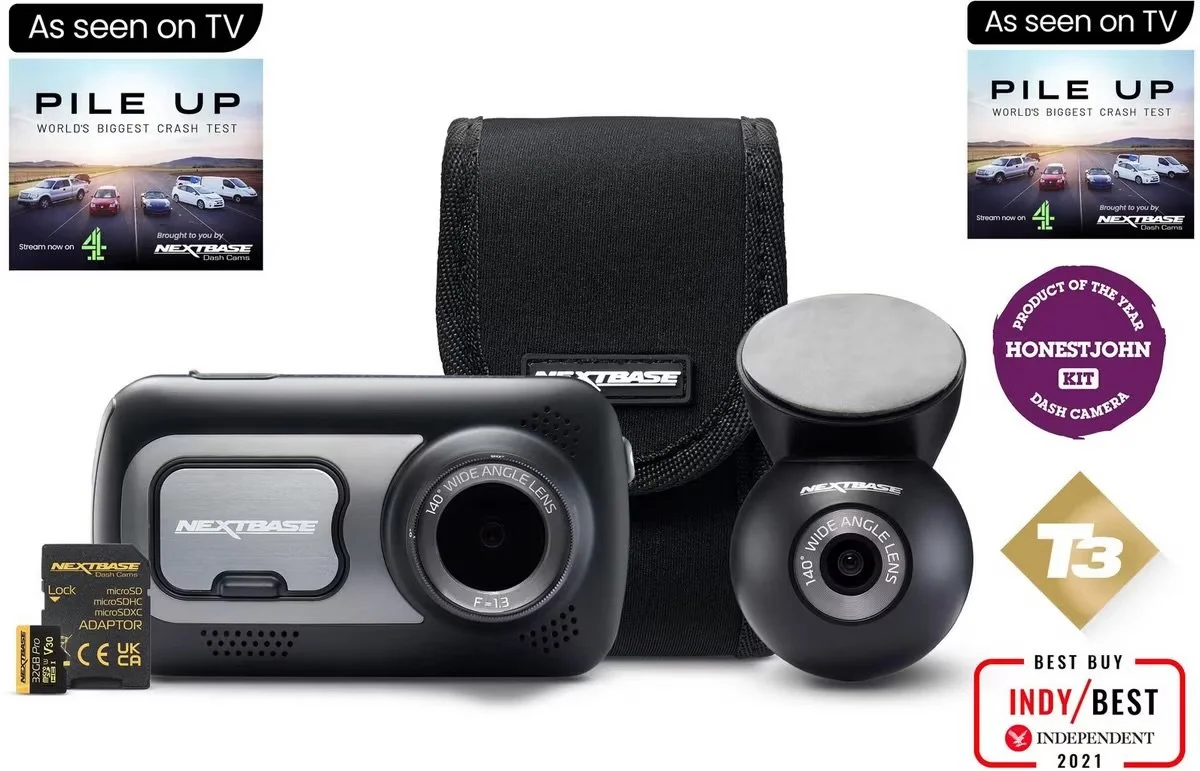 A dash camera kit from Nextbase with a main camera unit, a secondary camera, a carrying case, a microSD card, and promotional labels. Includes awards and TV advertising tags.