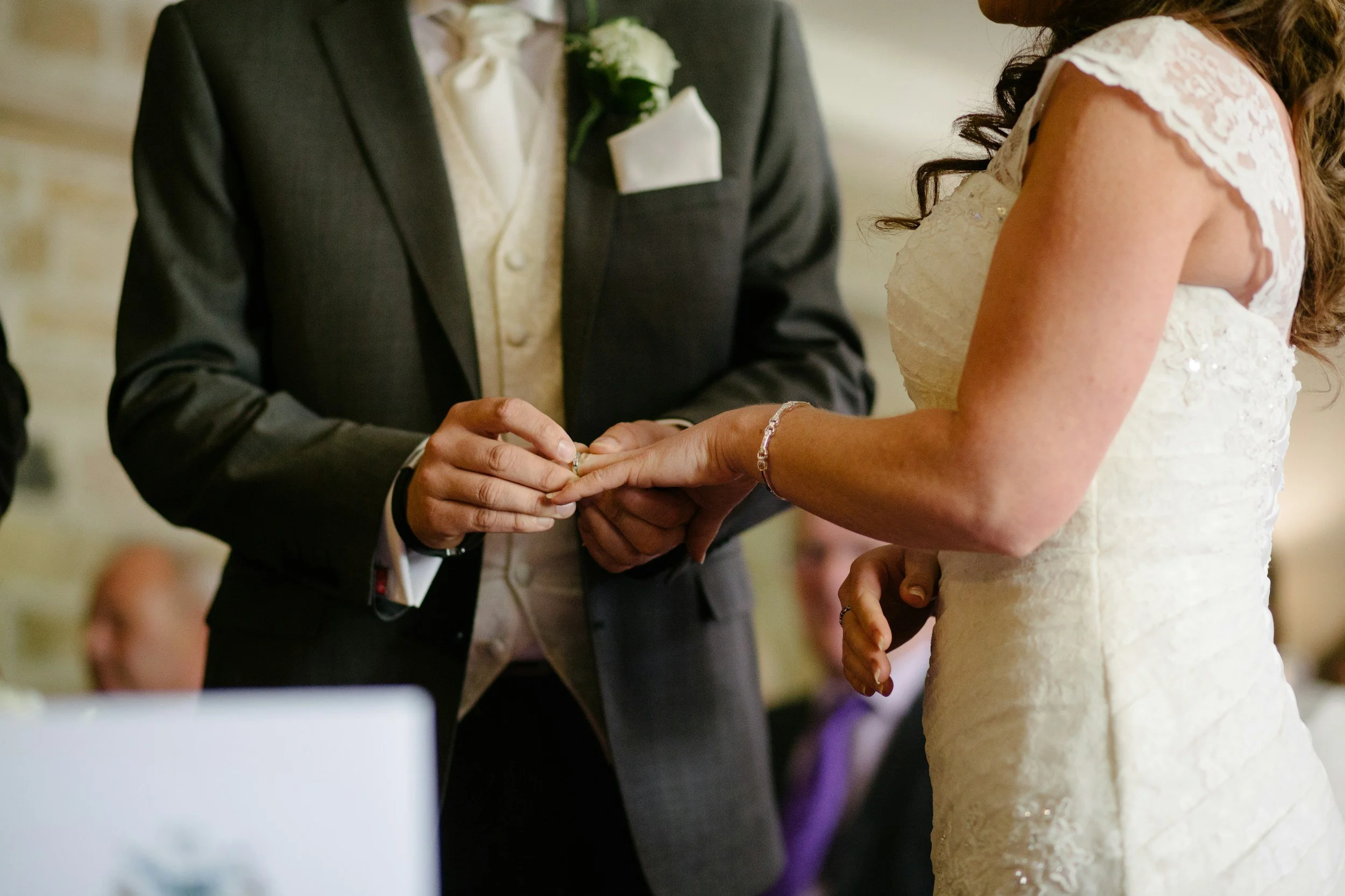 A groom placing a wedding ring on the bride's finger during a wedding ceremony.