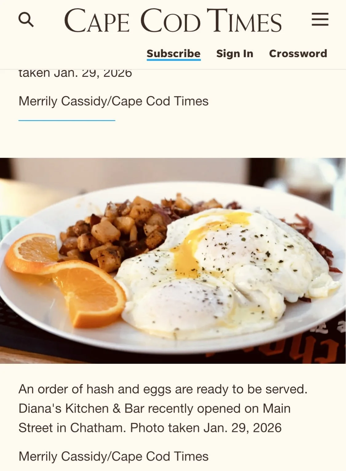 Plate with hash browns, two sunny side up eggs, and orange slices at a restaurant.