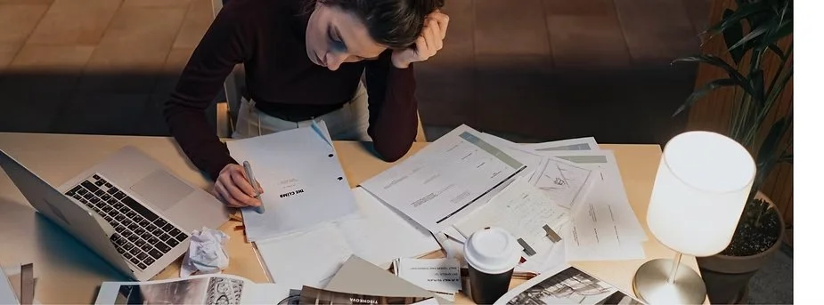 Woman feeling overwhelmed while working on business forms and paperwork.