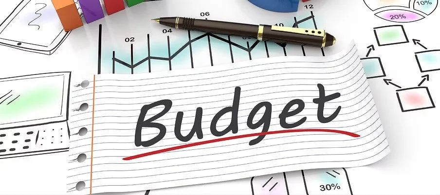 Flash card with “Budget” written on it against a background of financial illustrations.