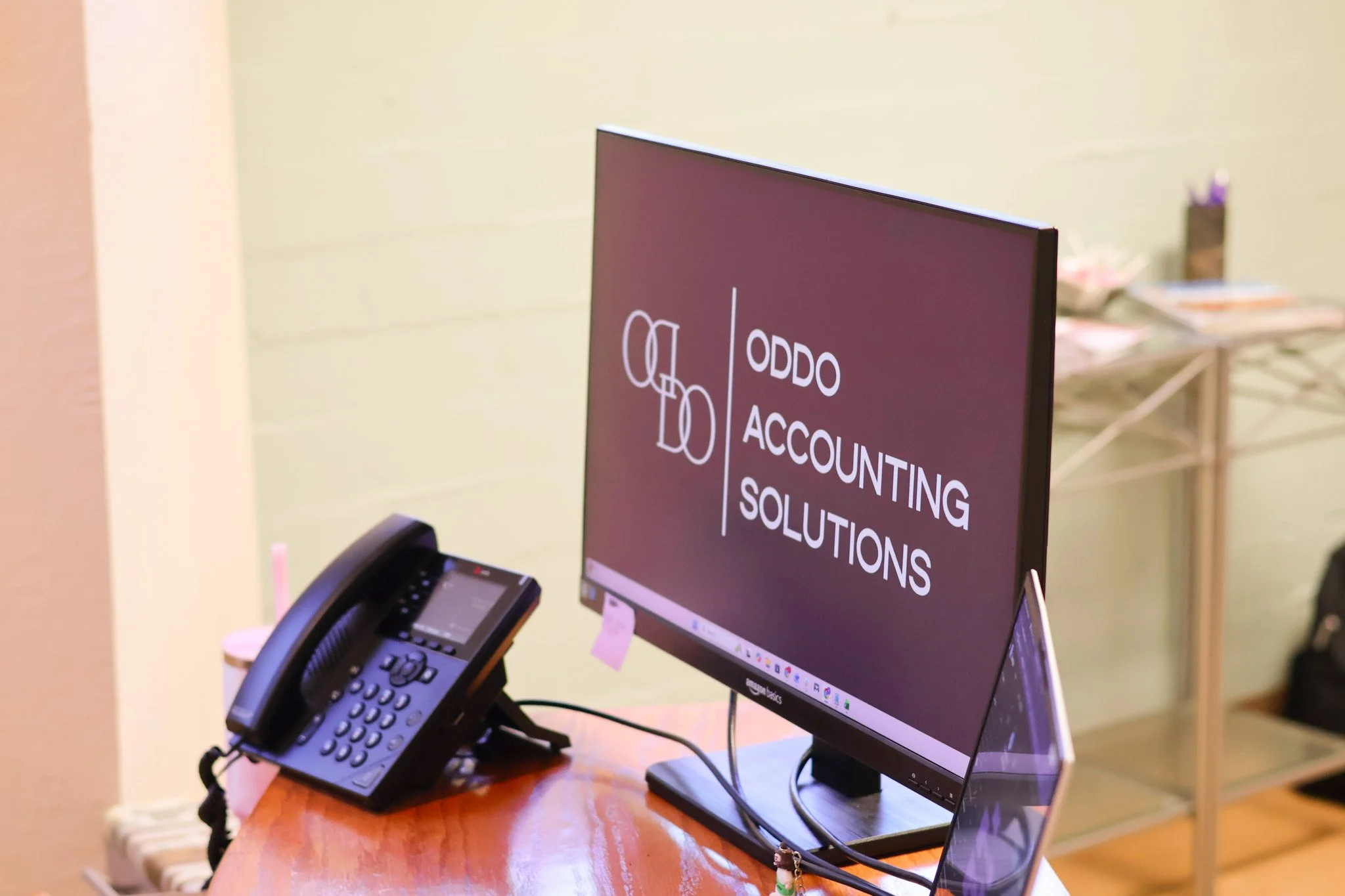 Office desk with a computer monitor displaying a sign titled 'Accounting Solutions' and a black office phone next to it.