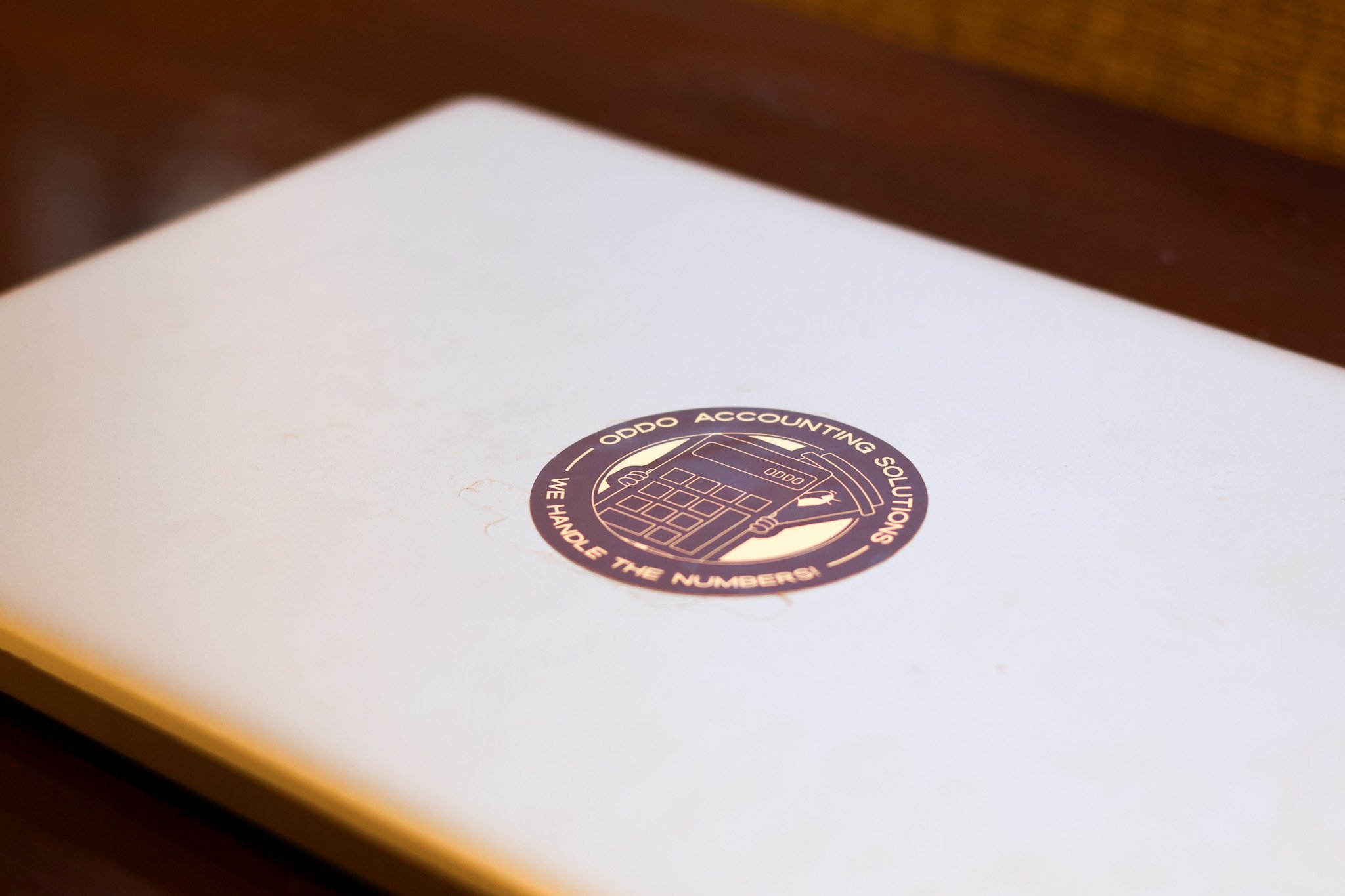 A white surface with a circular sticker from Oddo Accounting Solutions, featuring a calculator and the words 'We handle the numbers'.