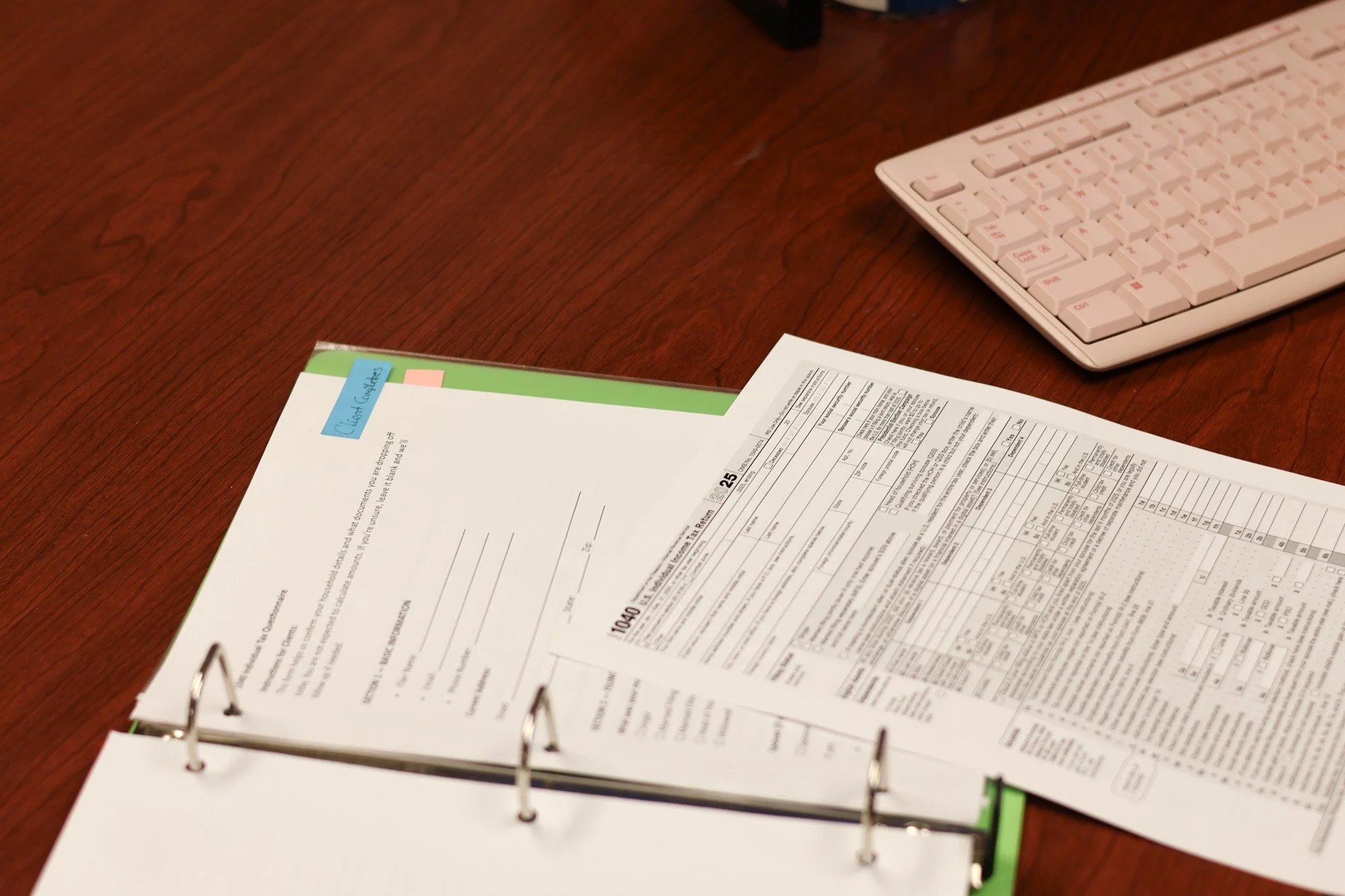Open binder with documents on a wooden desk, a white keyboard is in the upper right corner.