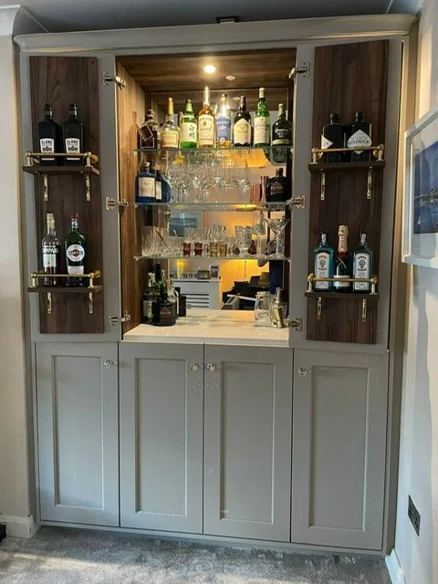 A home bar cabinet with bottles of liquor, glassware, and bar accessories inside