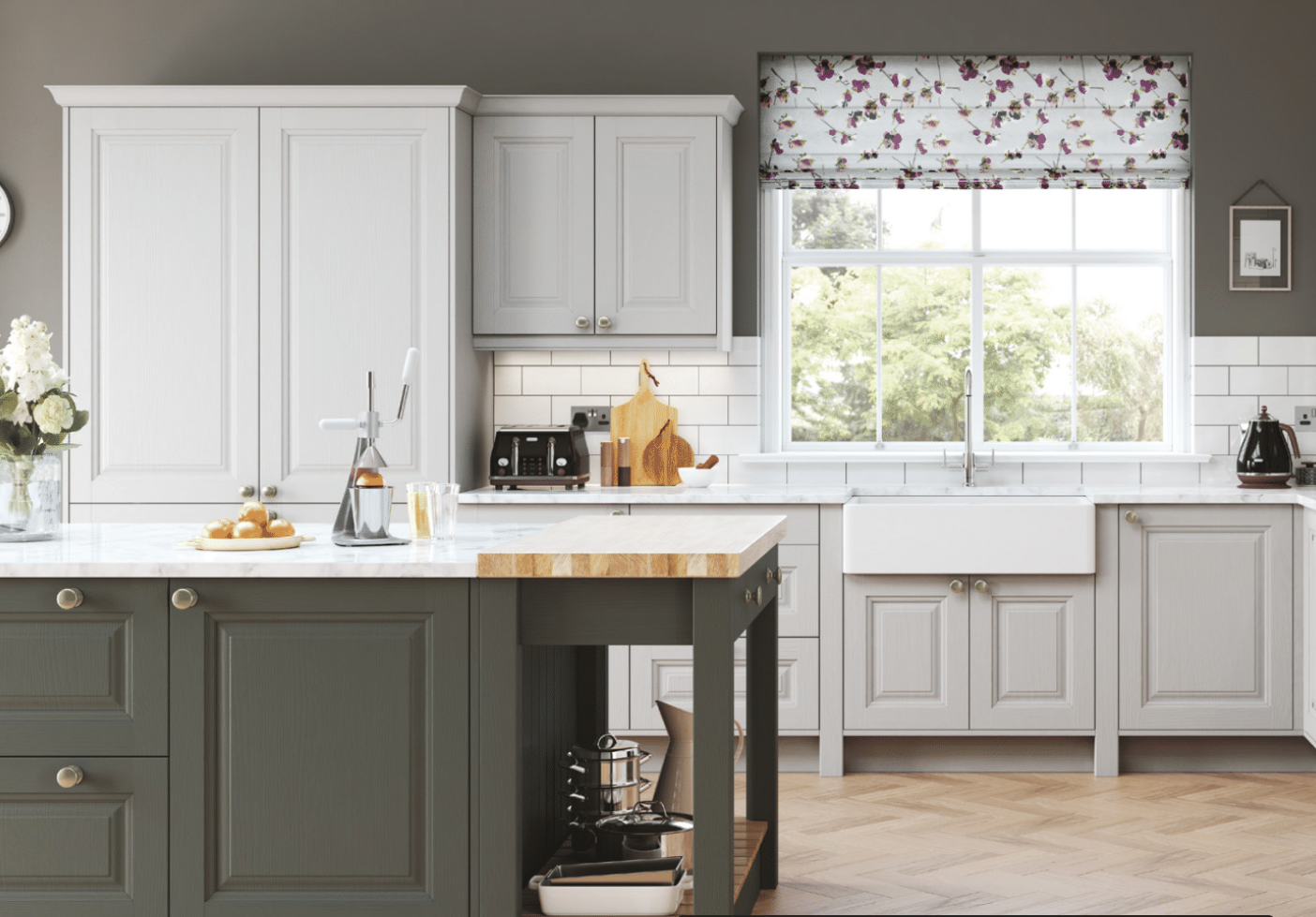 A modern kitchen with white cabinets, a large window with floral Roman shades, a kitchen island with a gray base, and various small appliances and decor.