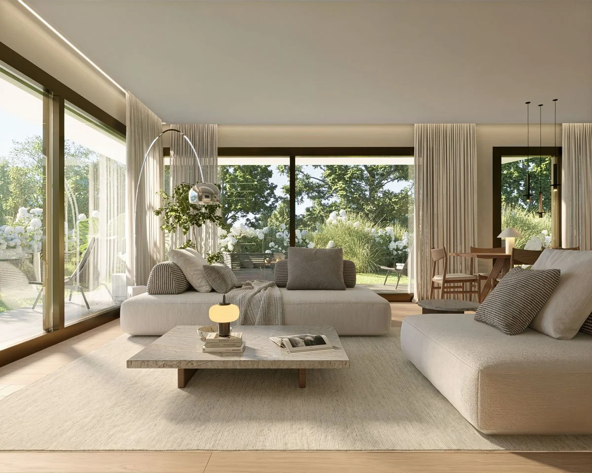 Living room con grandi finestre che mostrano un giardino con piante e fiori, arredato con divani beige, cuscini, tavolino in pietra, lampade e tende beige.