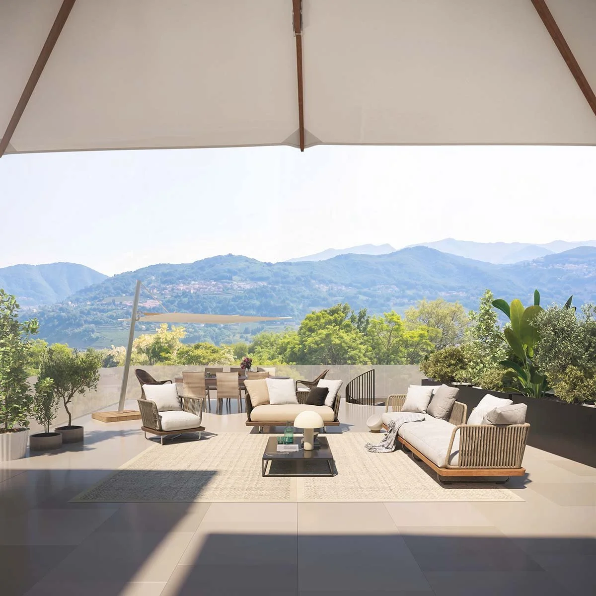 Balcone con vista sulle montagne, arredato con divani e poltrone moderne, ombra di grande ombrello, piante verdi e veduta naturale sullo sfondo.