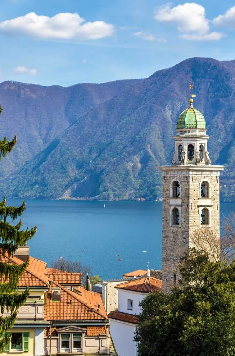 Lugano, torre con orologio e cupola di rame con un paesaggio lacustre e montagne sullo sfondo