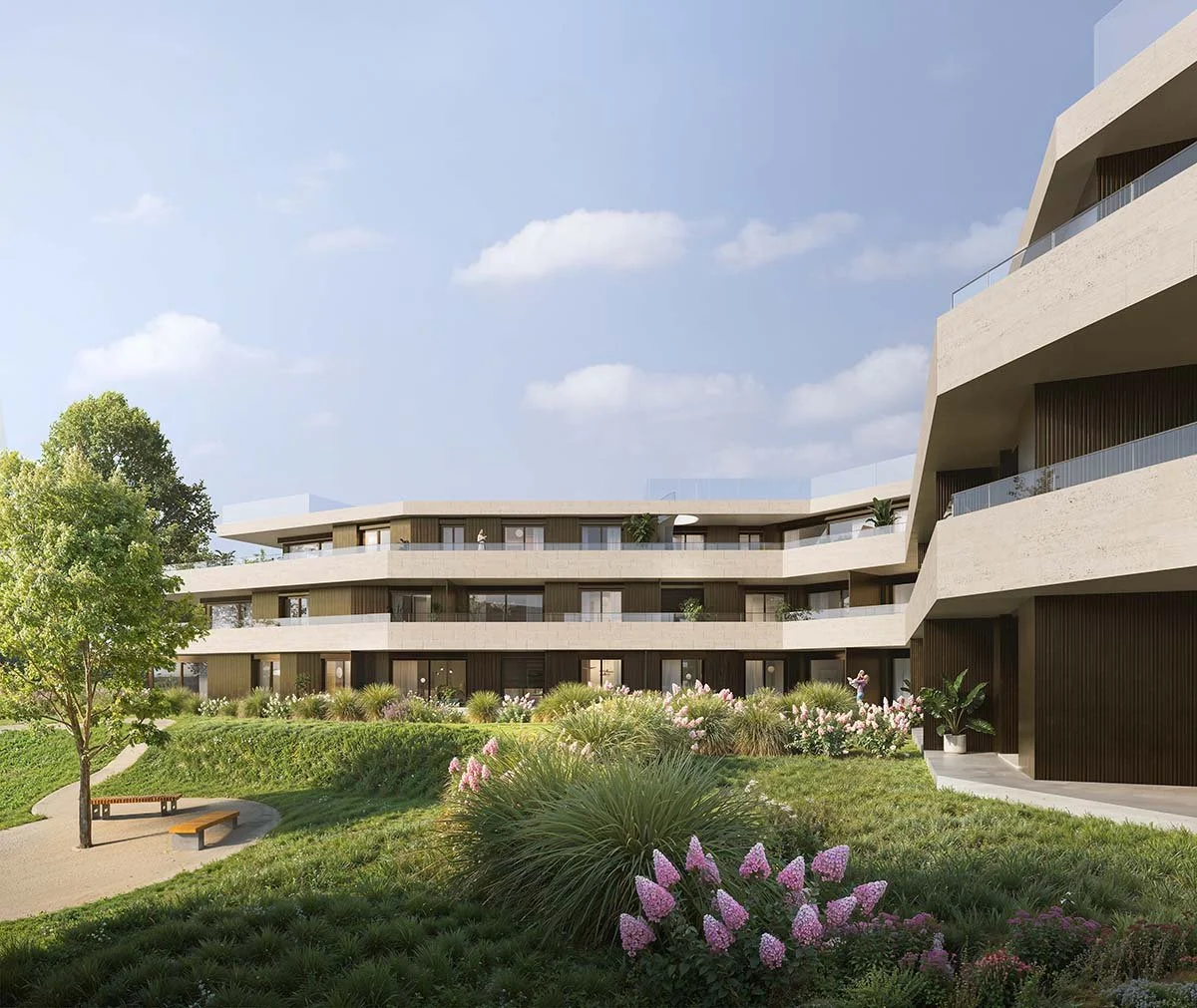 Complesso di edifici residenziali moderni con giardino curato, panchine e alberi, sotto un cielo azzurro con alcune nuvole.