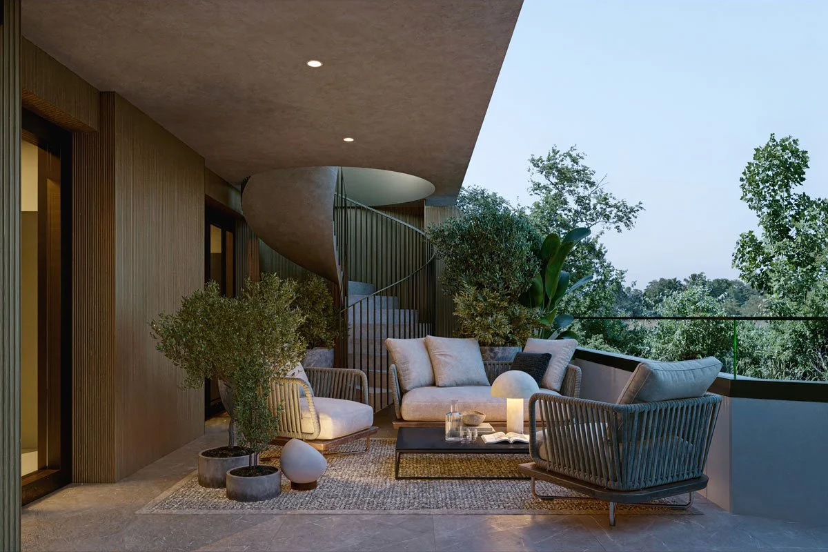 Balcone arredato con divani e poltrone, piante, lampada, tavolino e vista su alberi.