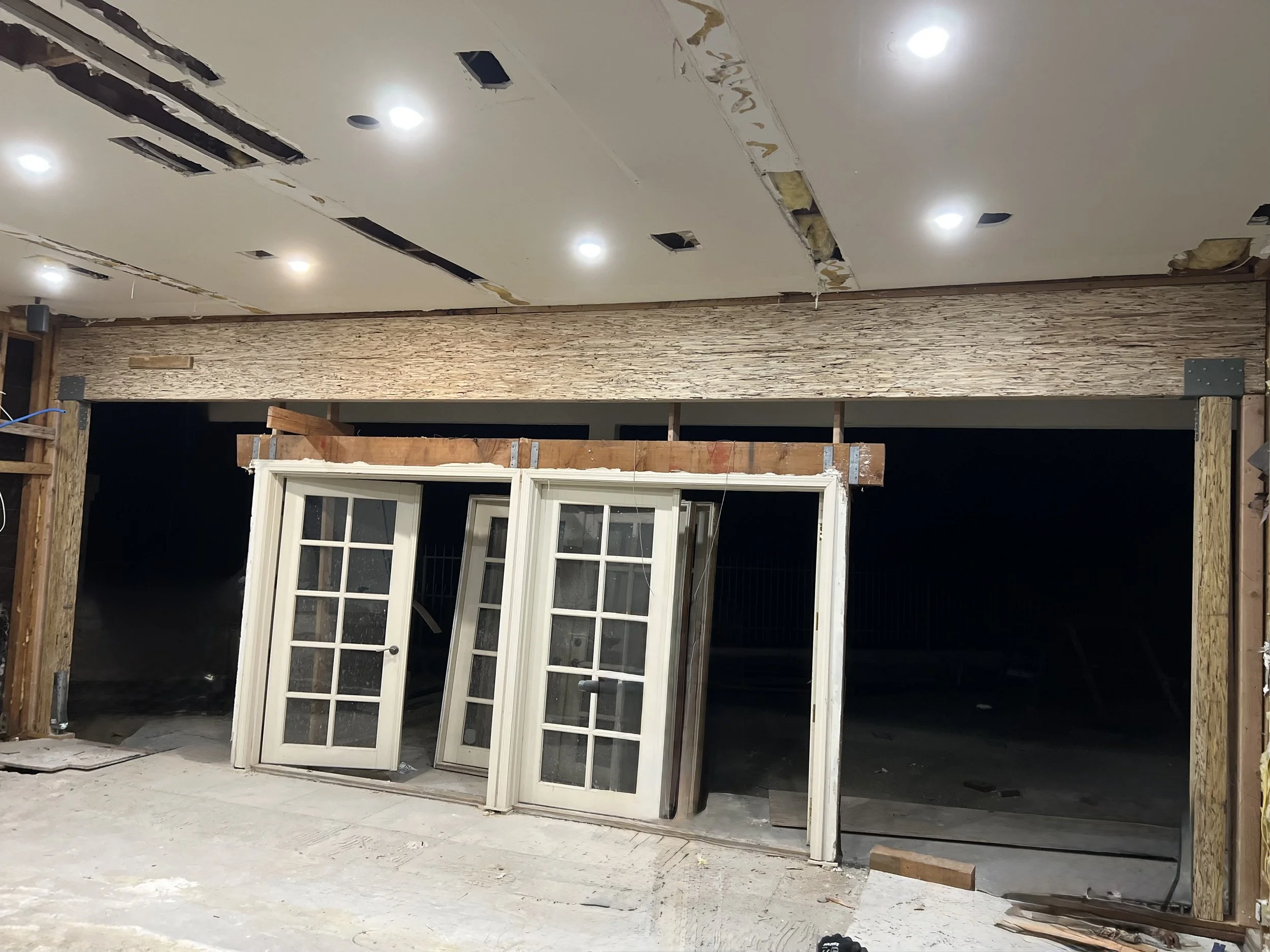 .“Renovation of an unfinished room showing existing French doors, with a new structural beam and support post