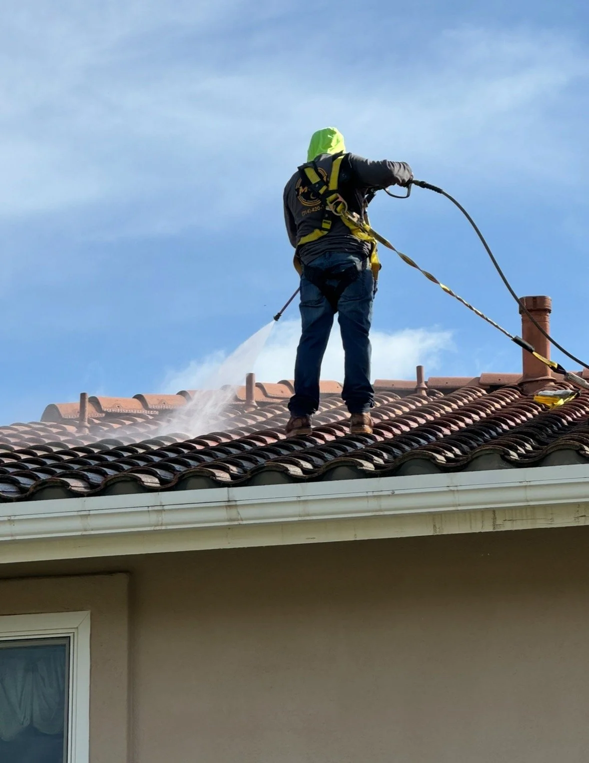 “Using a pressure washing tool to clean the roof, removing dirt and debris to prevent moss buildup, which helps protect the roof and extend its lifespan.”