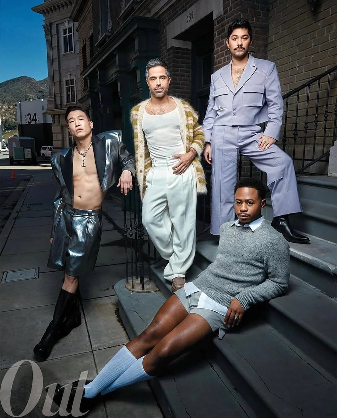 Five diverse individuals pose on the steps of a building, dressed in a mix of stylish and casual fashion, with city street and hills in the background.