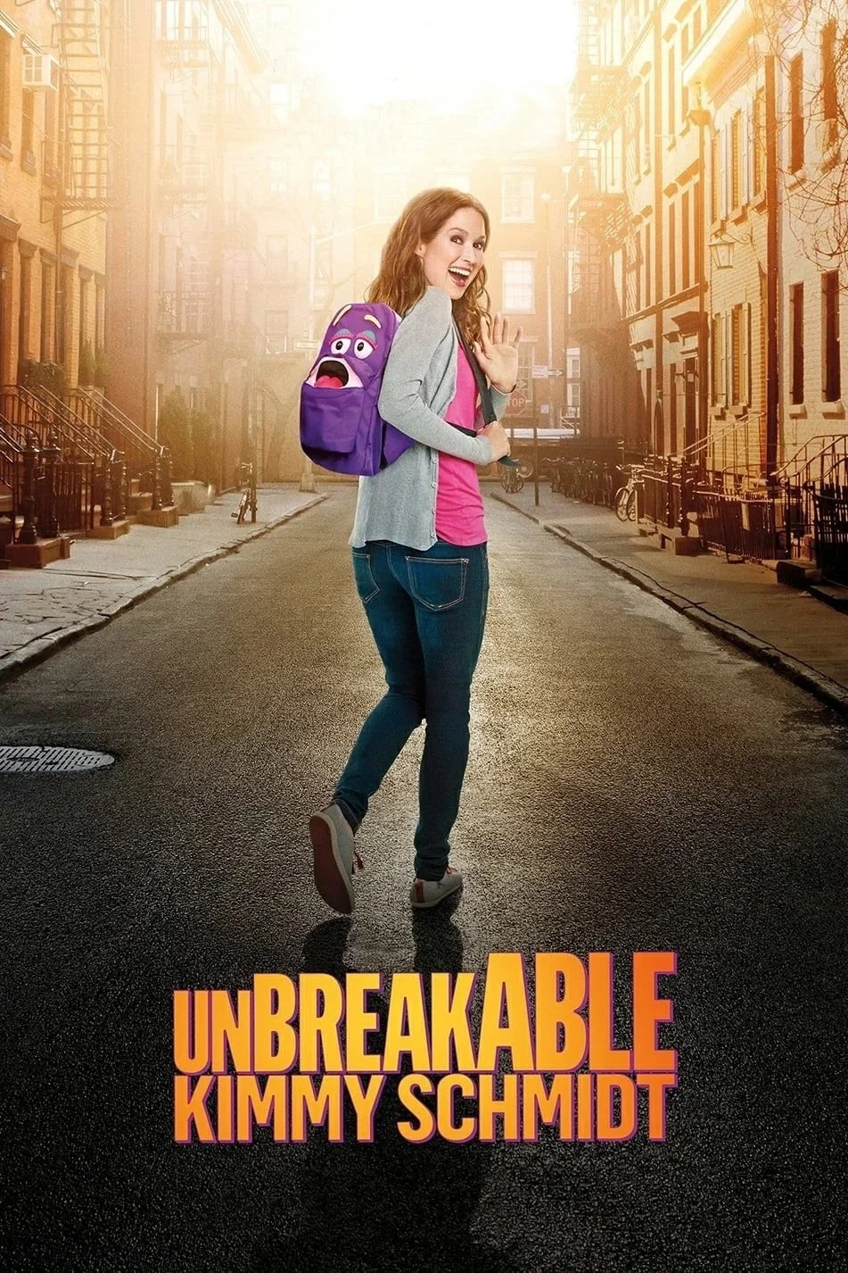 A young woman with red hair waving and smiling in the middle of a city street at sunset, carrying a purple backpack with a cartoon face. The street is lined with stairs and brownstone buildings, and the movie title "Unbreakable Kimmy Schmidt" is at t