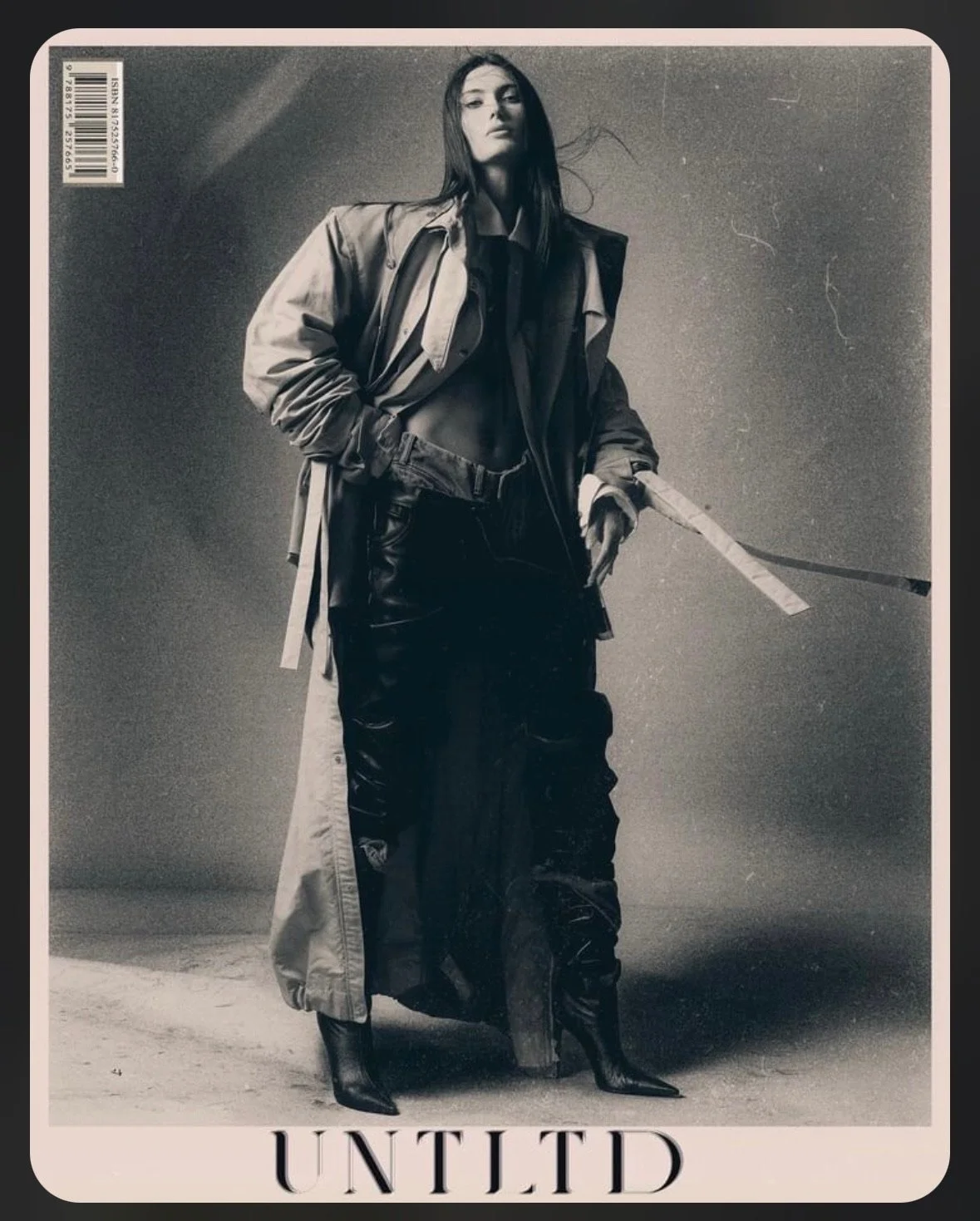 Black and white fashion photograph of a woman in a long coat, high boots, and a relaxed pose. The word 'UNITED' is at the bottom of the image.