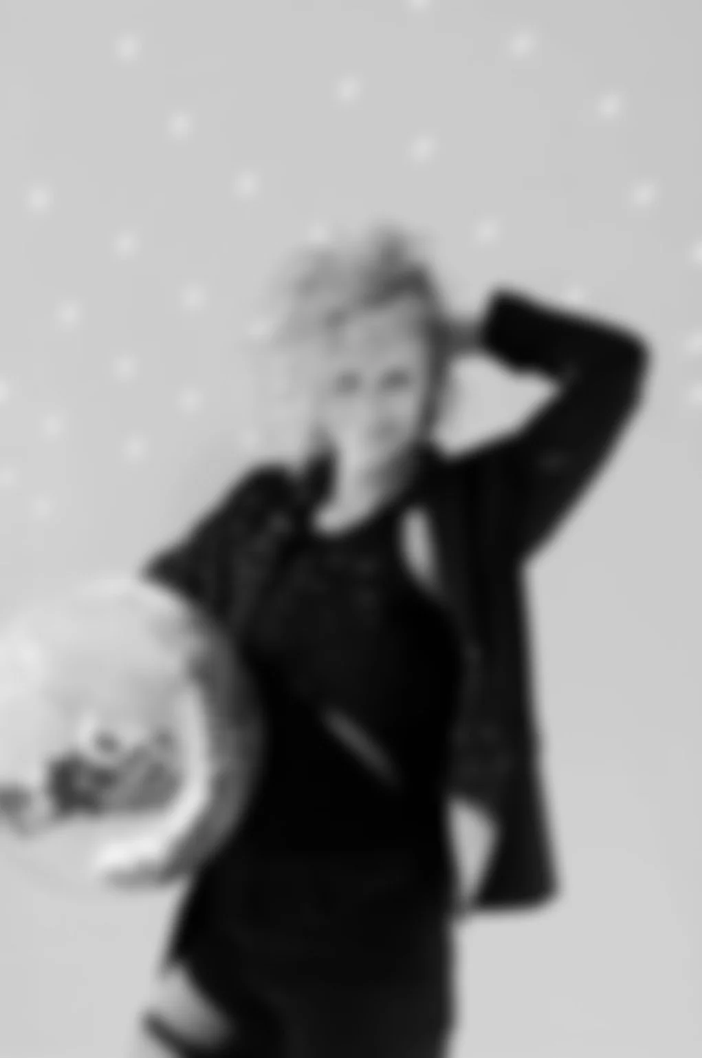 Black and white photo of a woman holding a skull prop in a studio setting with a dotted background.