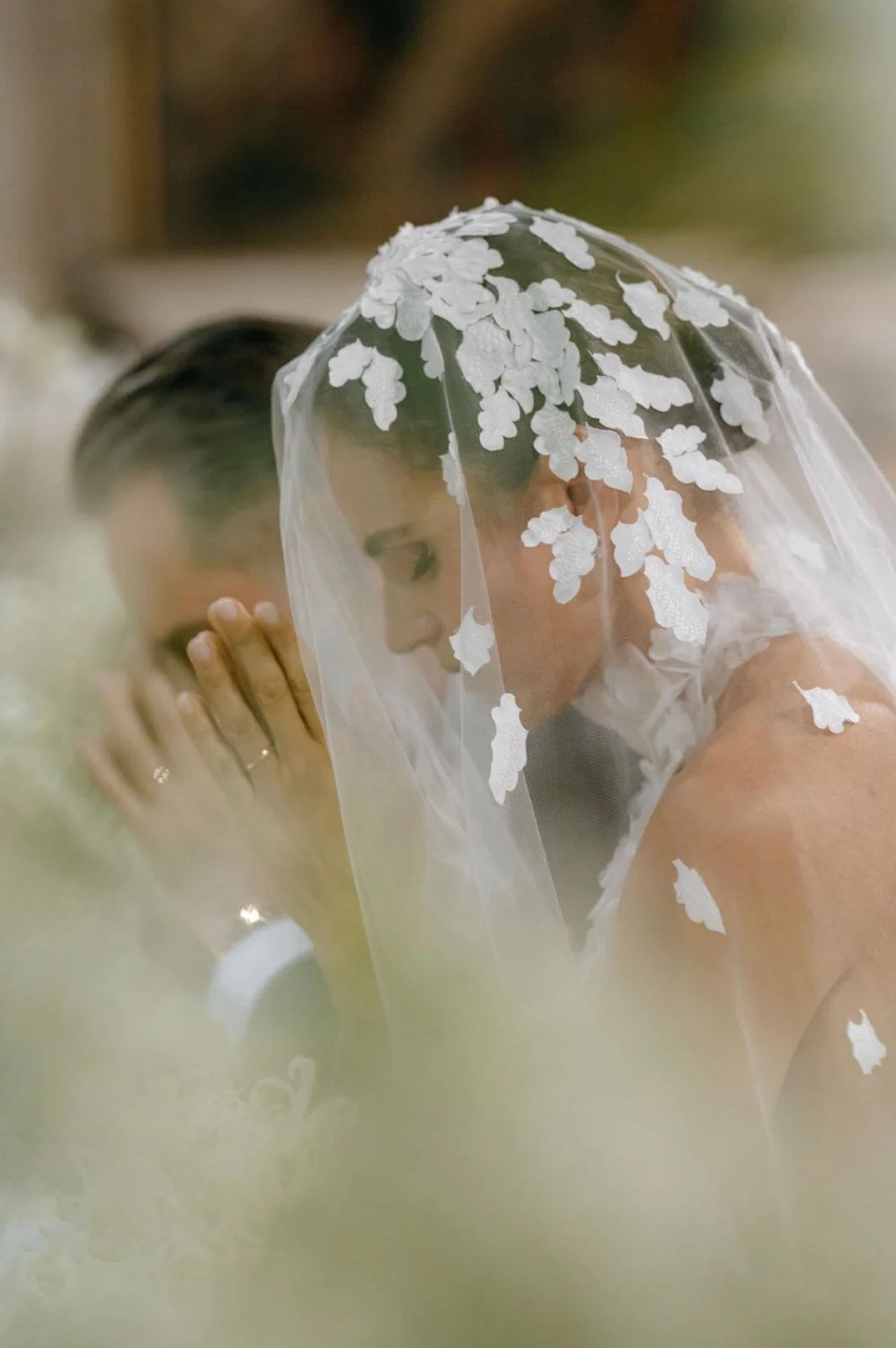 Due persone in atteggiamento di preghiera, una con un velo bianco decorato con fiori, in un contesto di matrimonio.