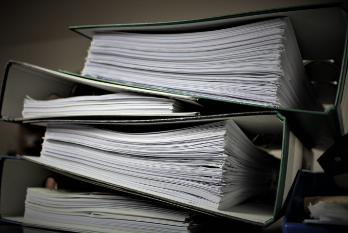 Three binders filled with papers stacked on a desk