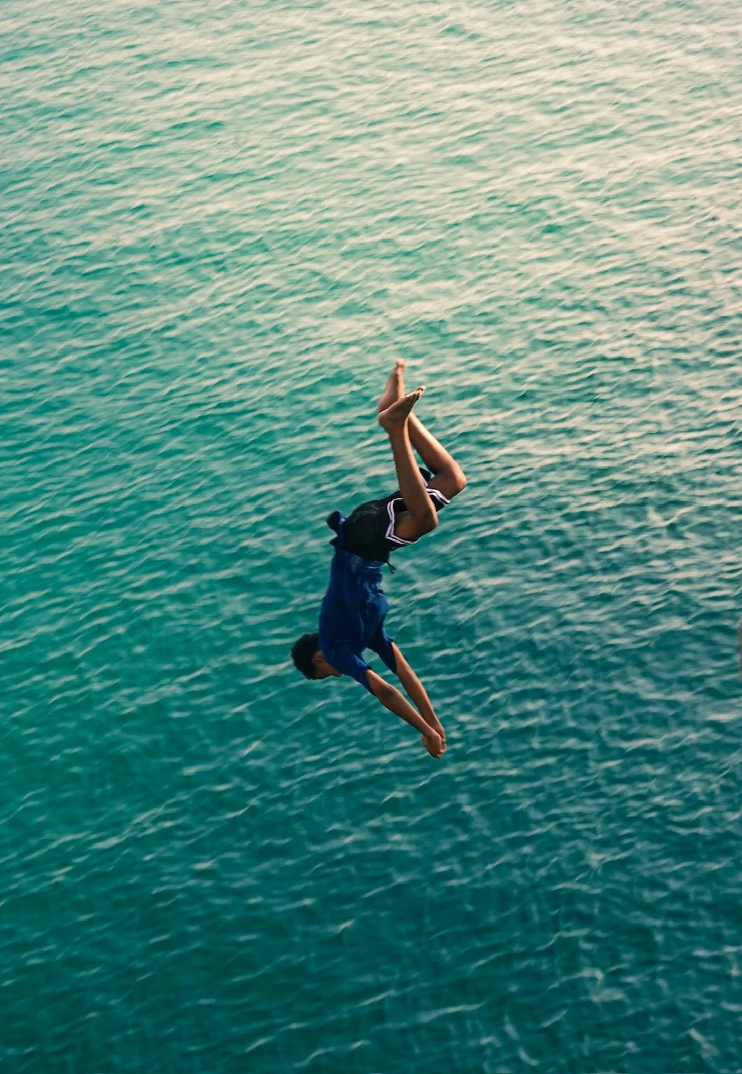 young boy dives off a bridge into the ocean - Sur, Oman