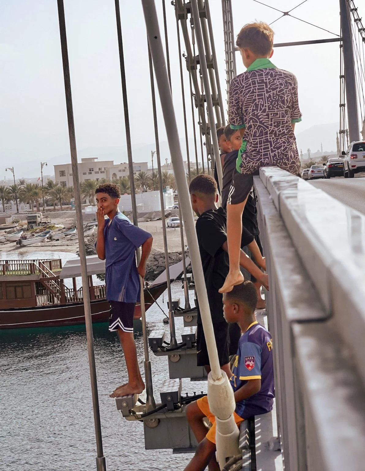 a boy blows the camera a kiss before he dives off a bridge in Oman